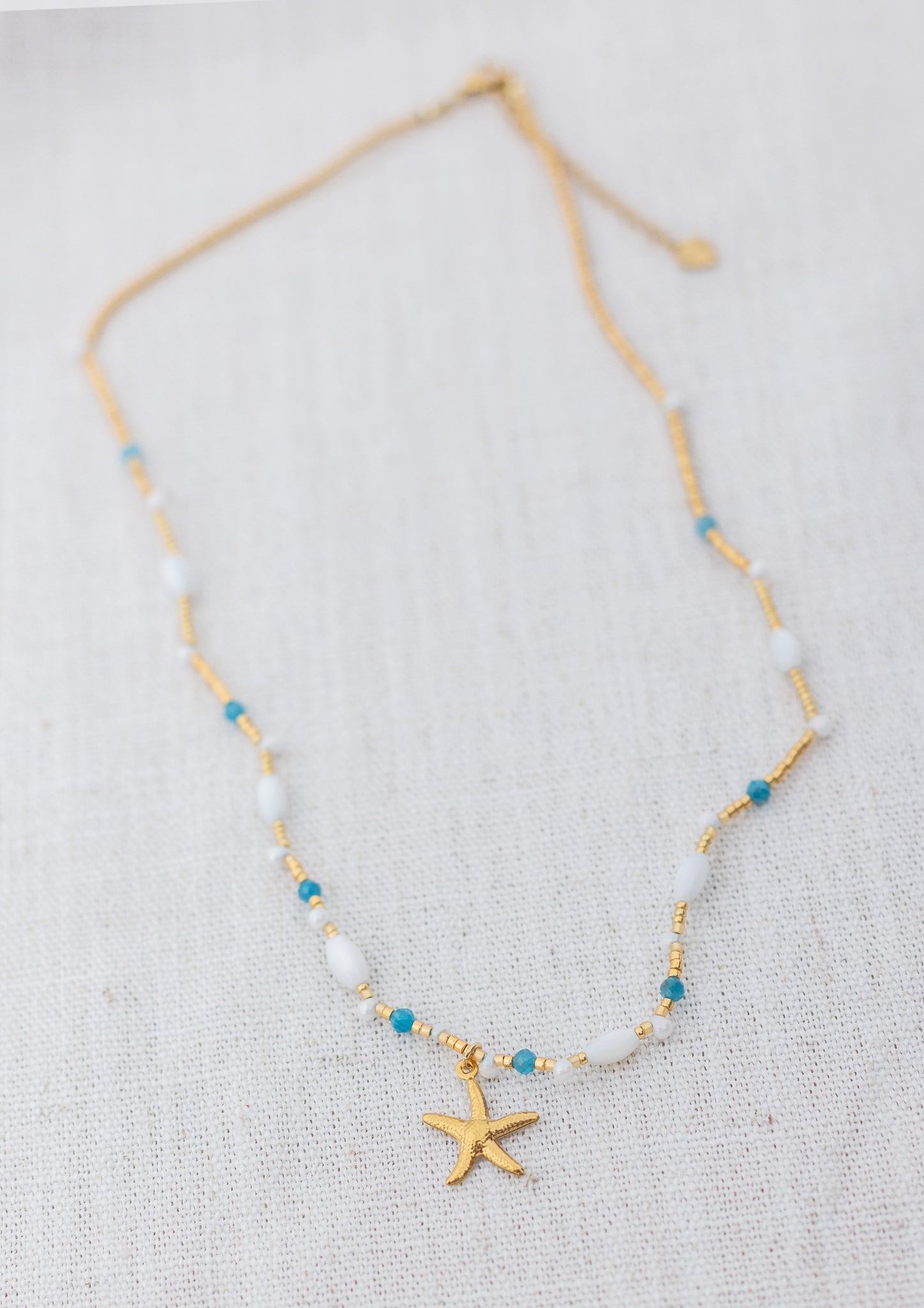 Intuitive Charms Delphina's Song Apatite Braided natural Crystal beaded custom necklace in gold on a light fabric background rectangle version