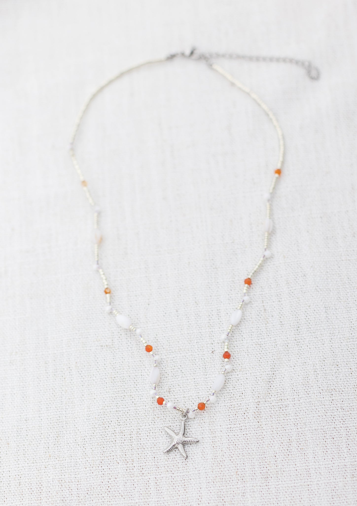 Intuitive Charms Coralia's Song Carnelian Braided natural Crystal beaded custom Bracelet in silver and clasp extension on a light fabric background rectangle view