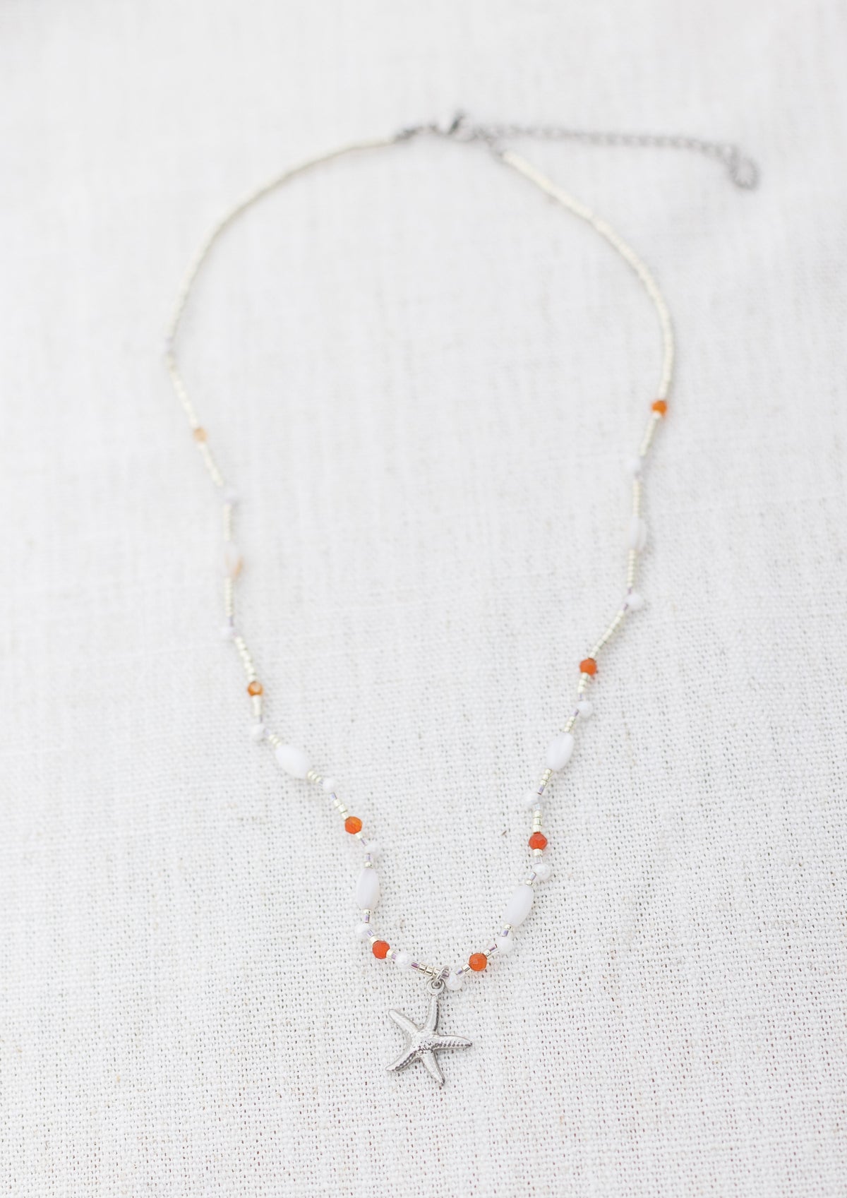 Intuitive Charms Coralia's Song Carnelian Braided natural Crystal beaded custom Bracelet in silver and clasp extension on a light fabric background rectangle view
