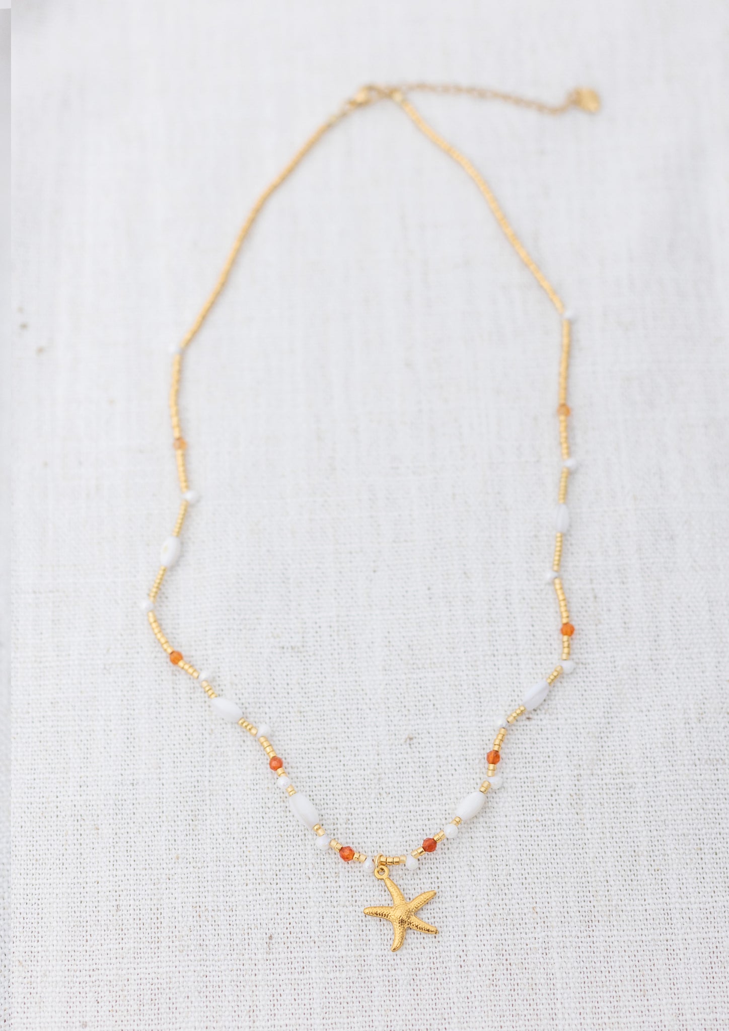 Intuitive Charms Coralia's Song Carnelian Braided natural Crystal beaded custom Bracelet in gold and clasp extension on a light fabric background rectangle view