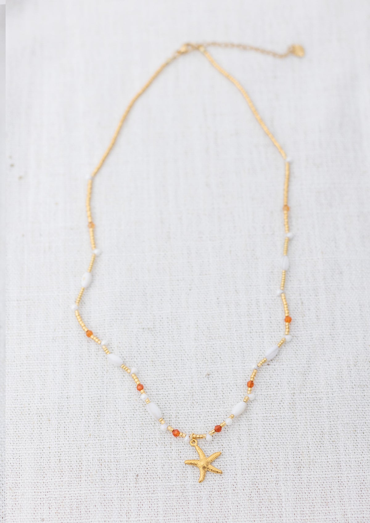 Intuitive Charms Coralia's Song Carnelian Braided natural Crystal beaded custom Bracelet in gold and clasp extension on a light fabric background rectangle view