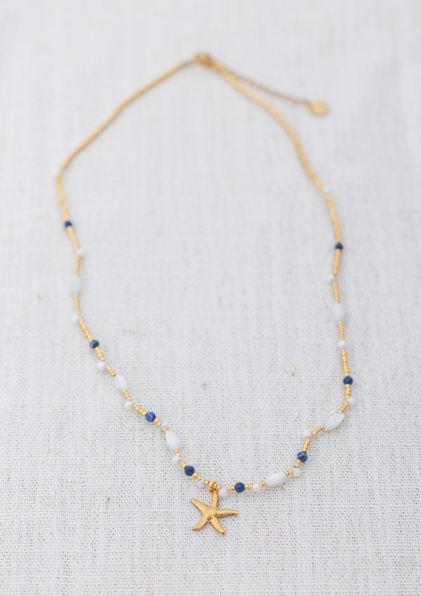 Intuitive Charms Amphitrite's Song Lapis Lazuli Braided natural Crystal beaded custom Bracelet in gold on a light fabric background rectangle version
