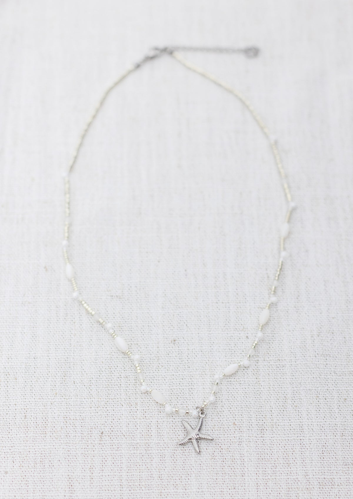 Intuitive Charms Selene's Song Moonstone natural Crystal beaded custom necklace in silver and clasp extension on a light fabric background rectangle view