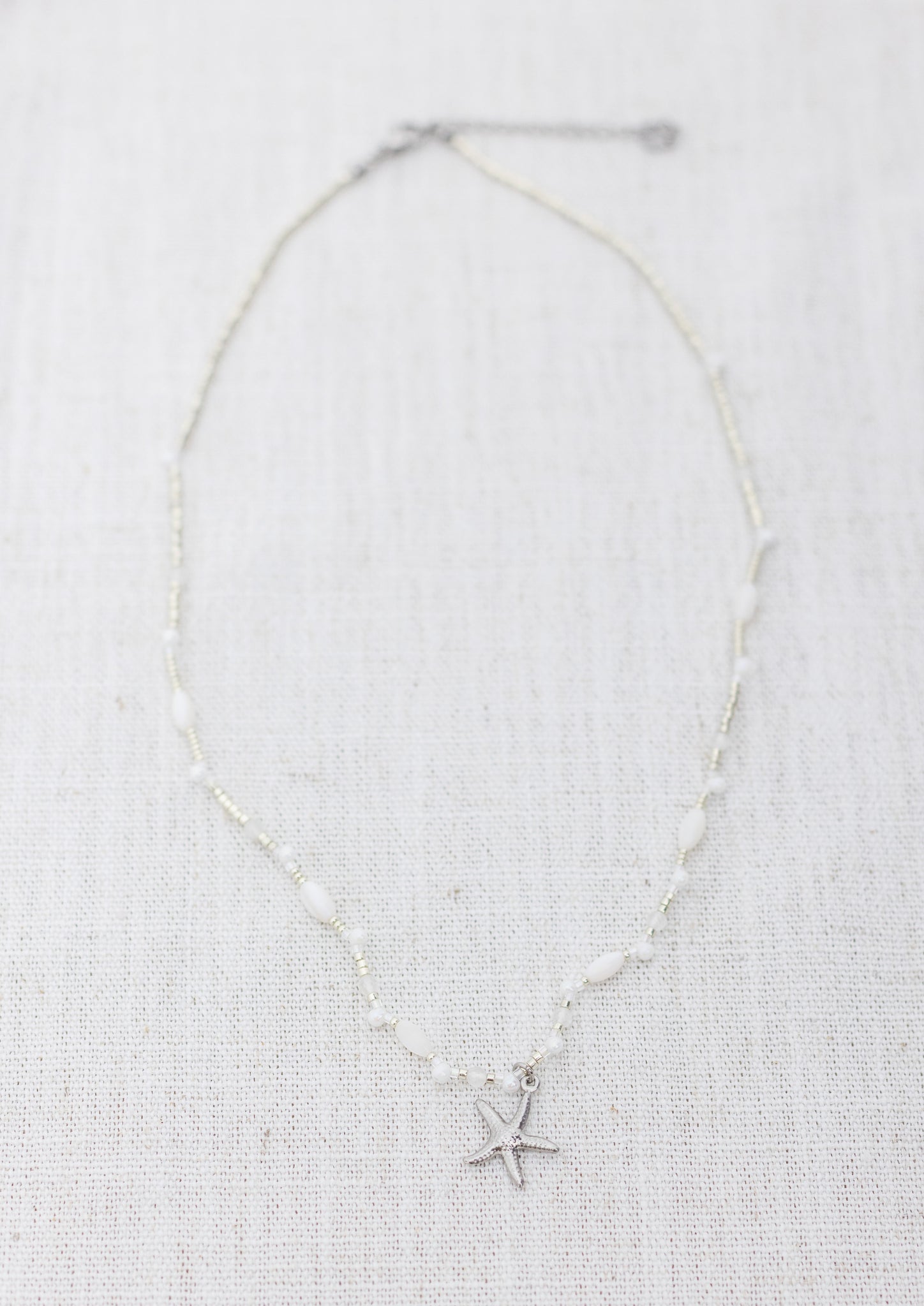 Intuitive Charms Selene's Song Moonstone natural Crystal beaded custom necklace in silver and clasp extension on a light fabric background rectangle view