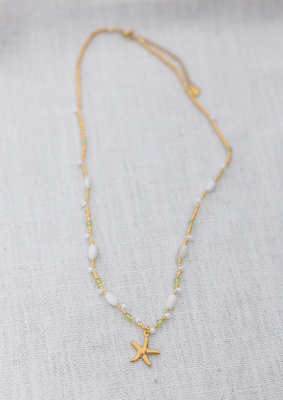 Intuitive Charms Nerina's Song Peridot natural Crystal beaded custom Bracelet in gold on a light fabric background rectangle version