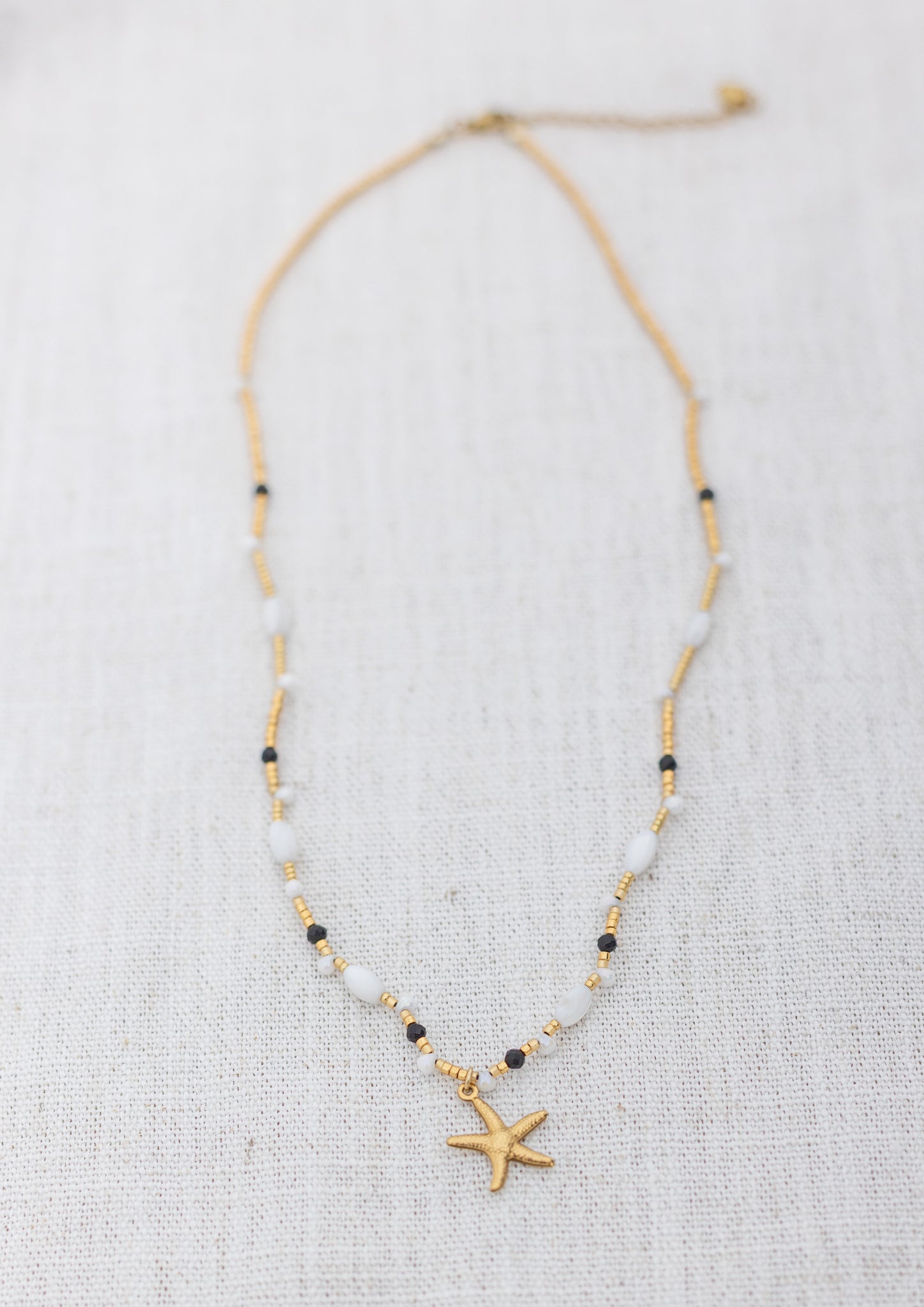 Intuitive Charms Ceto's Song Black tourmaline Braided natural Crystal beaded custom necklace in gold and black cord on a light fabric background rectangle version