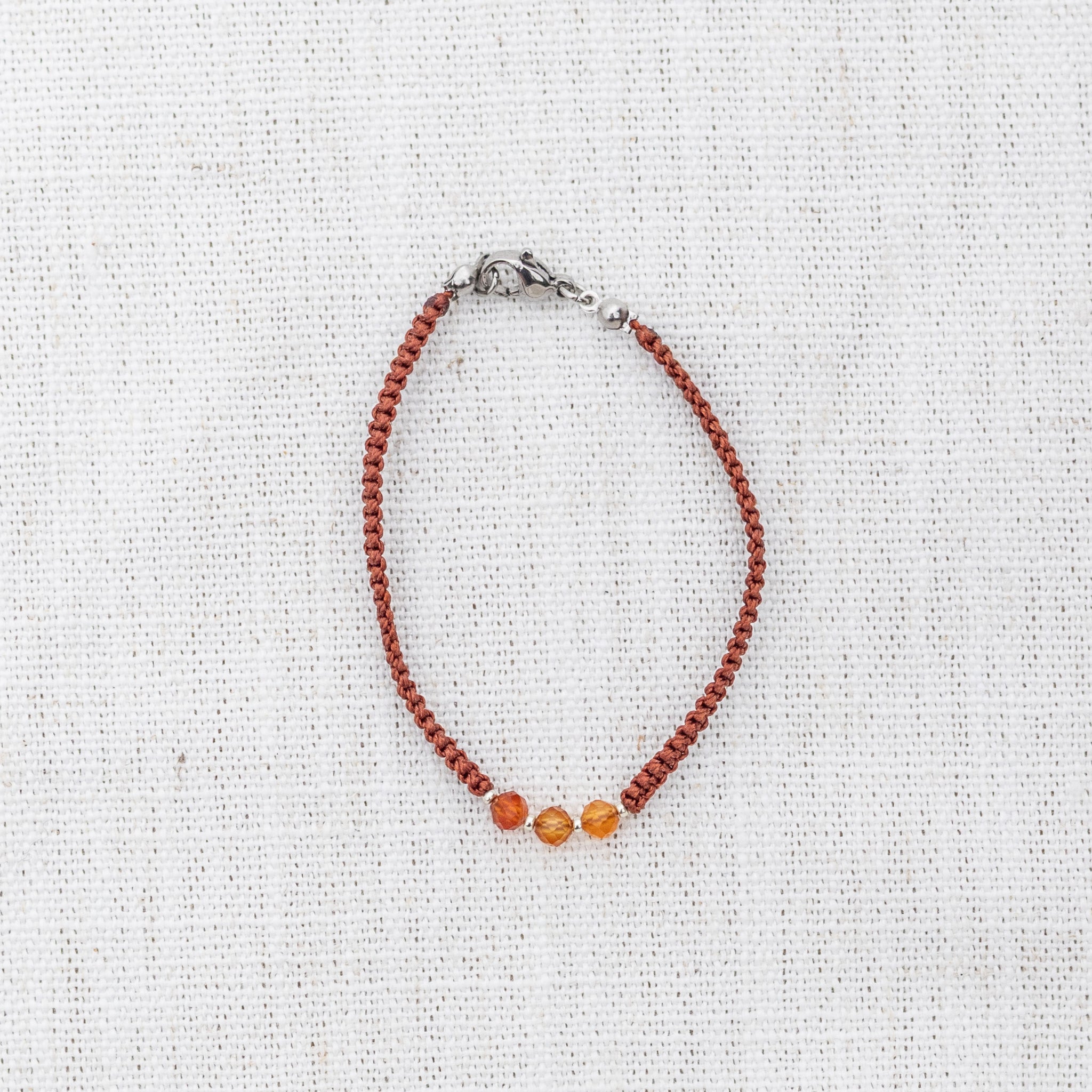 Intuitive Charms Coralia's Guard Carnelian Braided natural Crystal beaded custom Bracelet in silver and red cord and silver clasp on light fabric background