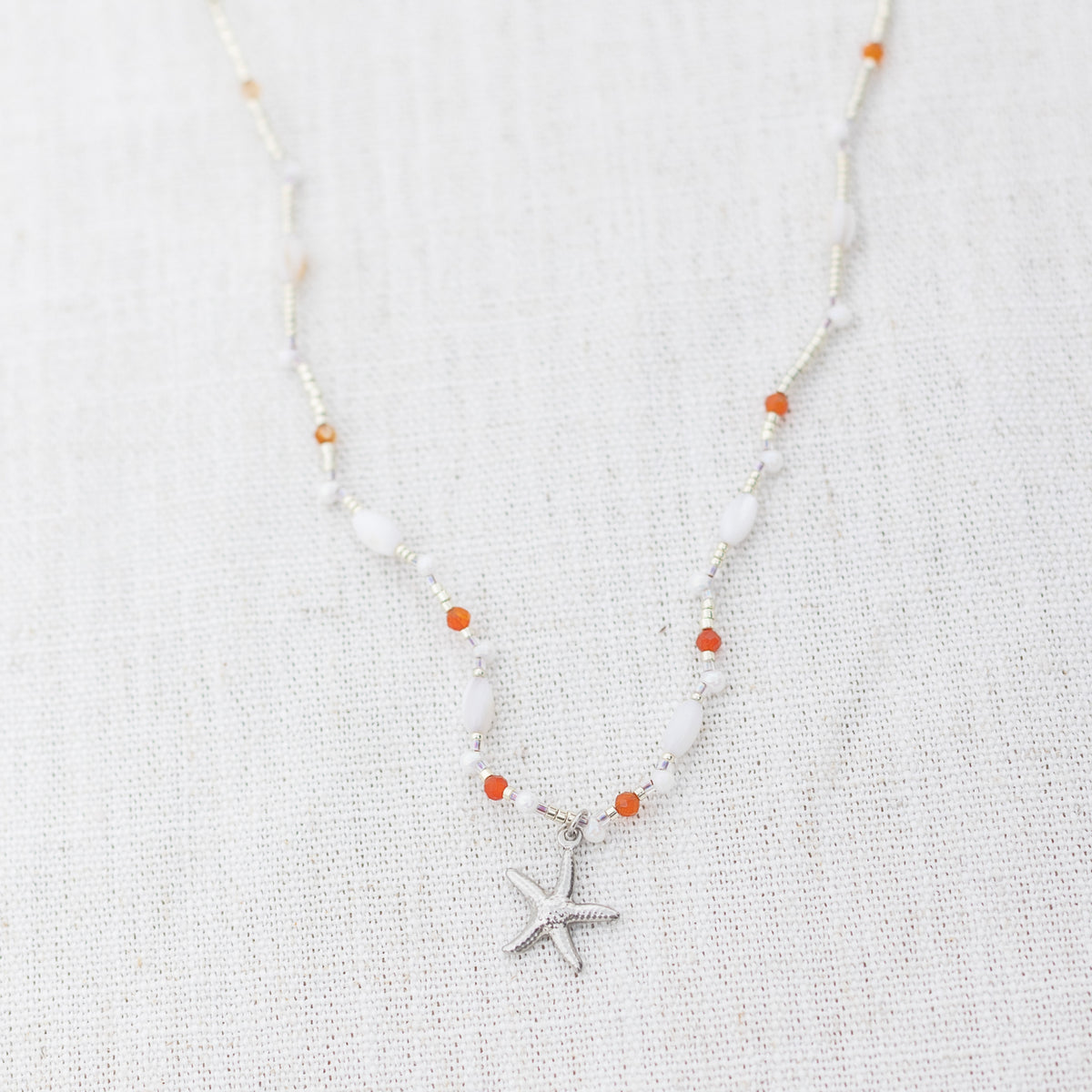 Intuitive Charms Coralia's Song Carnelian Braided natural Crystal beaded custom necklace in silver clasp extension on a light fabric background