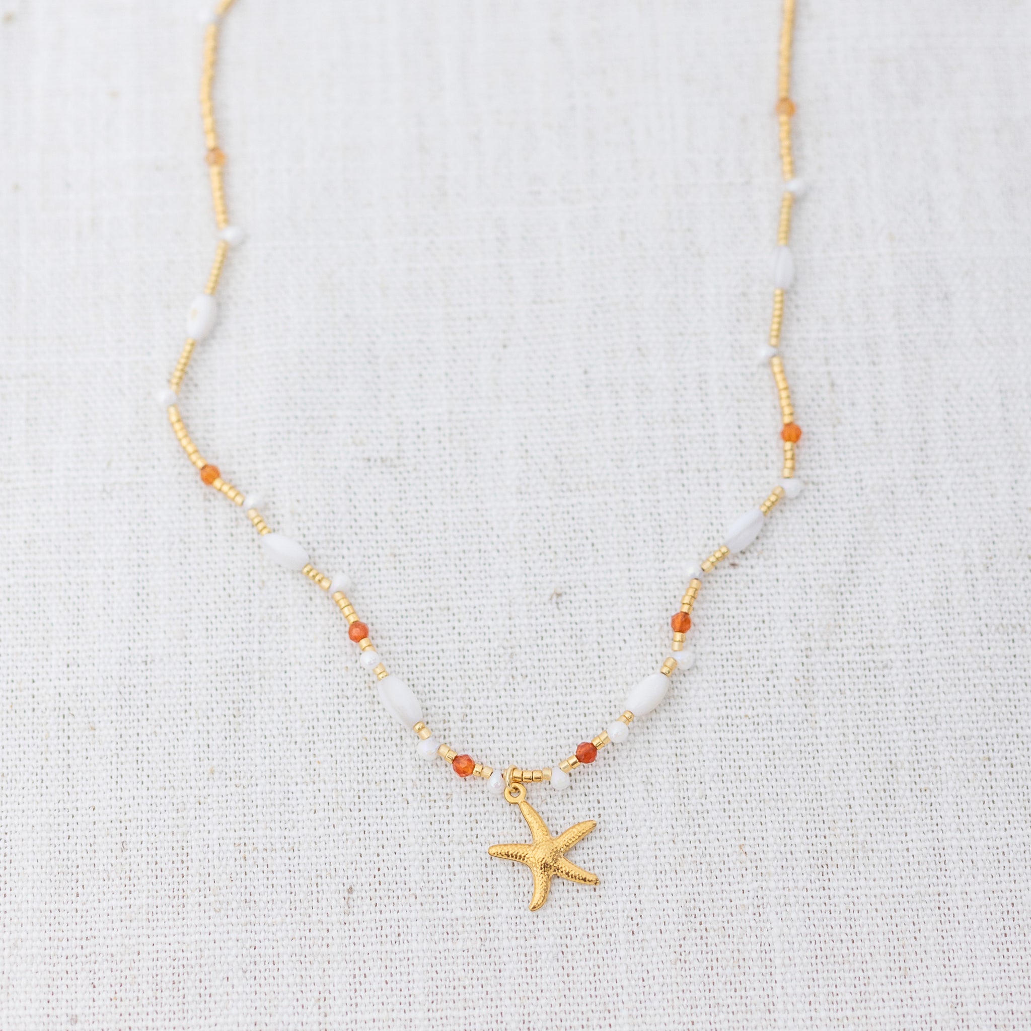 Intuitive Charms Coralia's Song Carnelian Braided natural Crystal beaded custom necklace in gold clasp extension on a light fabric background