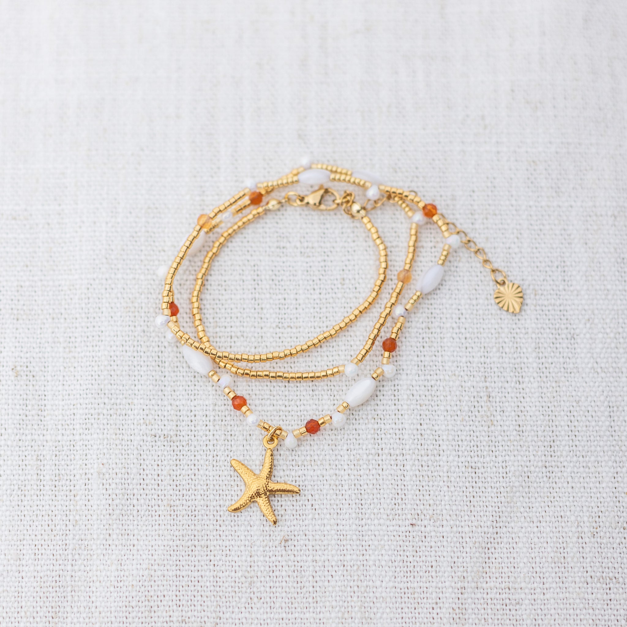 Intuitive Charms Coralia's Song Carnelian Braided natural Crystal beaded custom necklace in gold clasp extension on a light fabric background in wrapped version