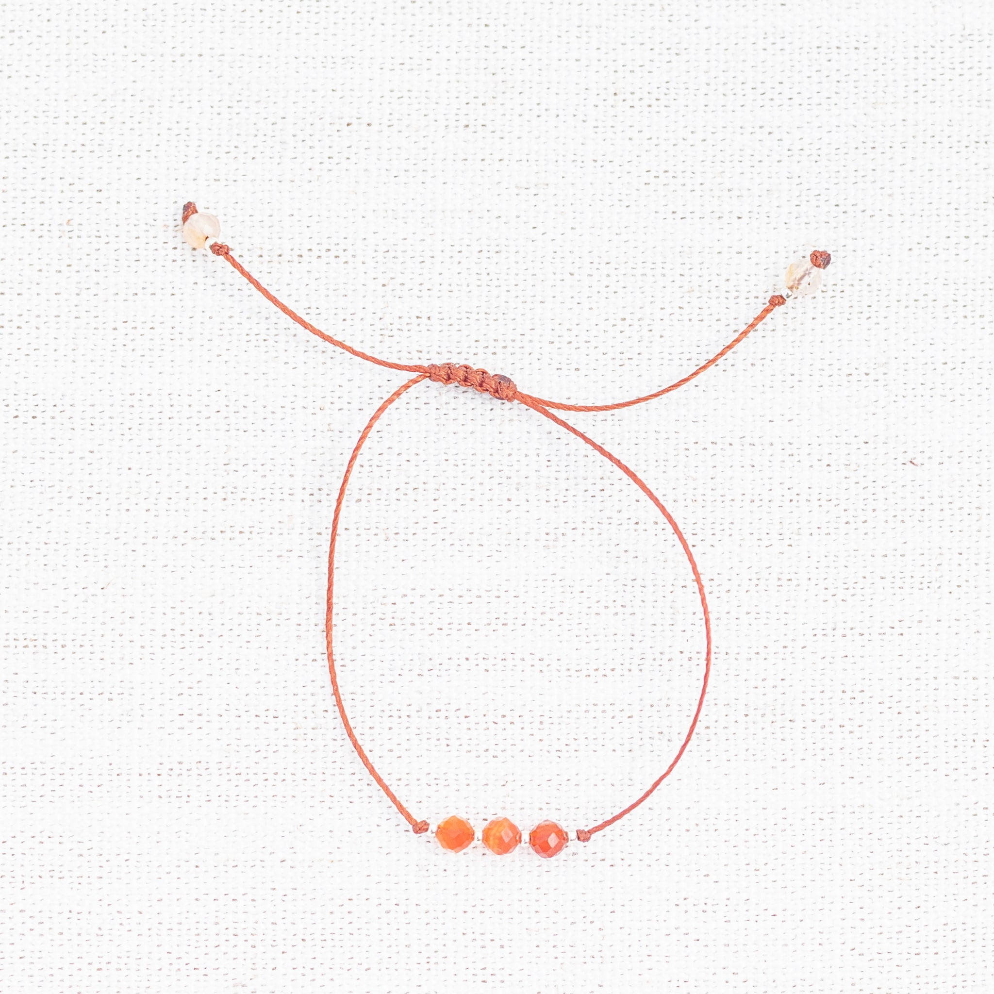 Intuitive Charms Coralia's Mist Carnelian Braided natural Crystal beaded custom Bracelet in silver and red cord on light fabric background