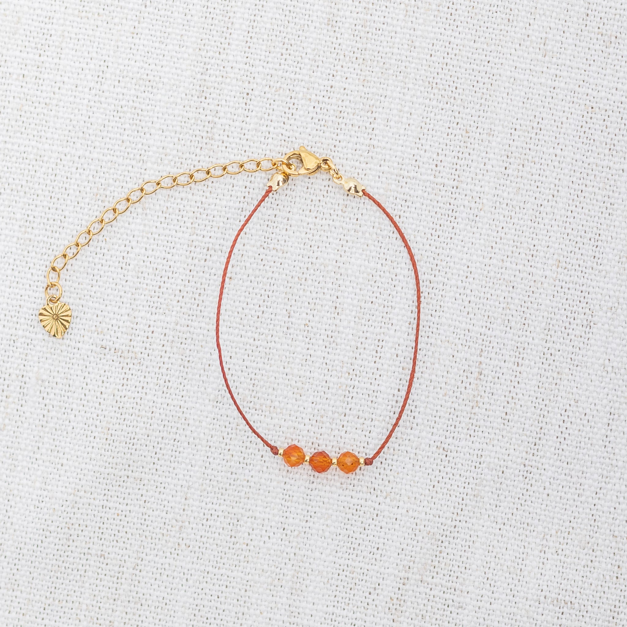 Intuitive Charms Coralia's Mist Carnelian Braided natural Crystal beaded custom Bracelet in gold and red cord and clasp extension on light fabric background