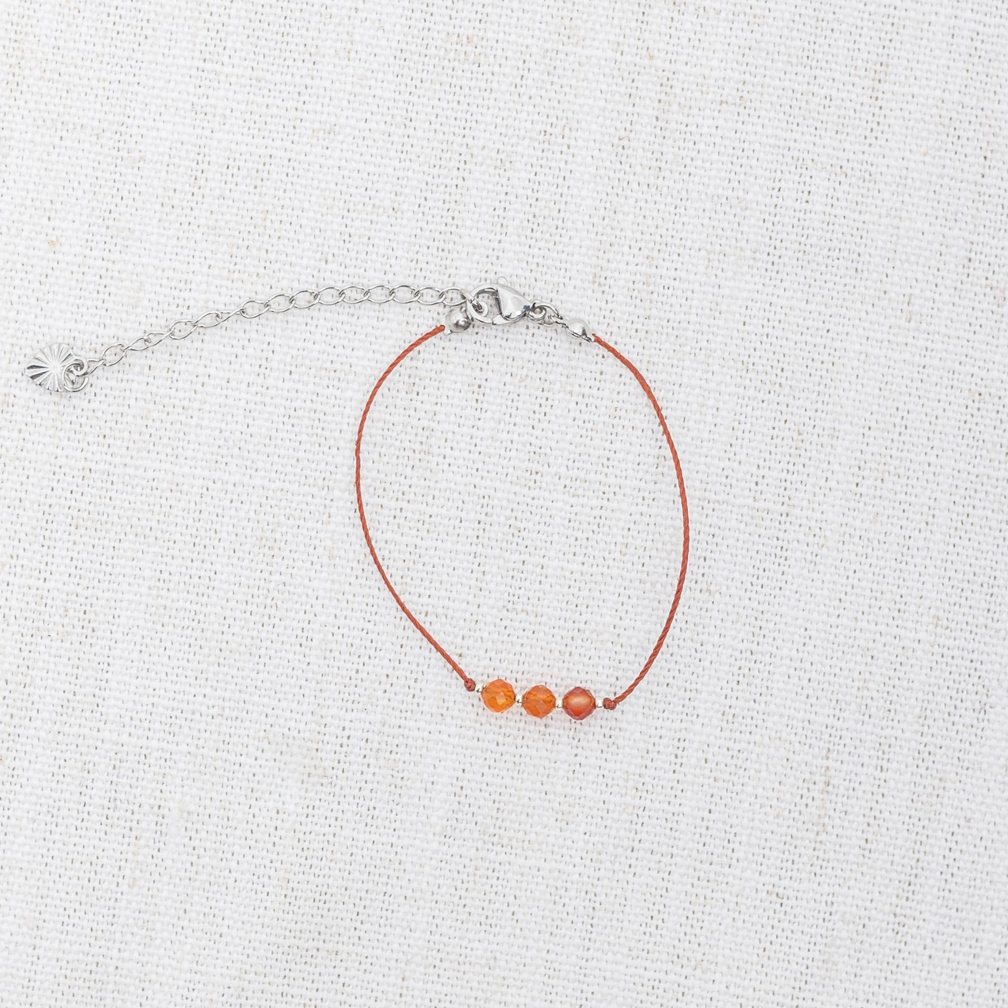 Intuitive Charms Coralia's Mist Carnelian Braided natural Crystal beaded custom Bracelet in silver and red cord and clasp extension on light fabric background