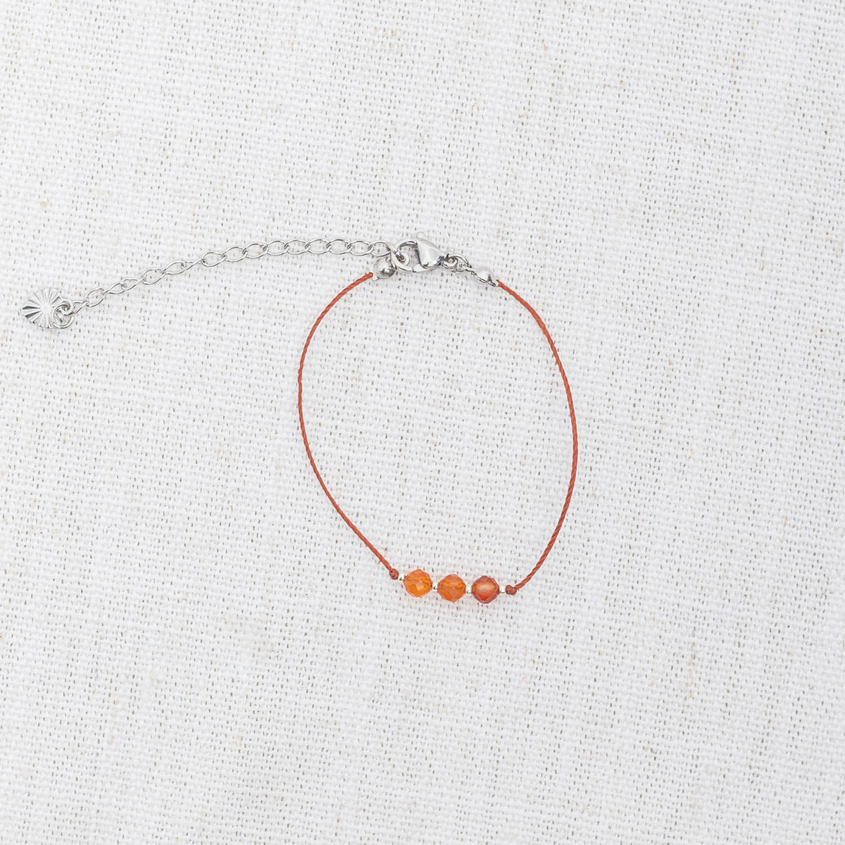 Intuitive Charms Coralia's Mist Carnelian Braided natural Crystal beaded custom Bracelet in silver and red cord and clasp extension on light fabric background