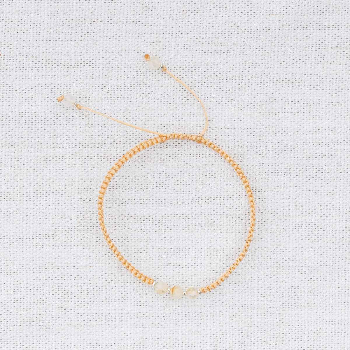 Intuitive Charms Eos's Guard Citrine Braided natural Crystal beaded custom Bracelet in silver and yellow cord on a light fabric background