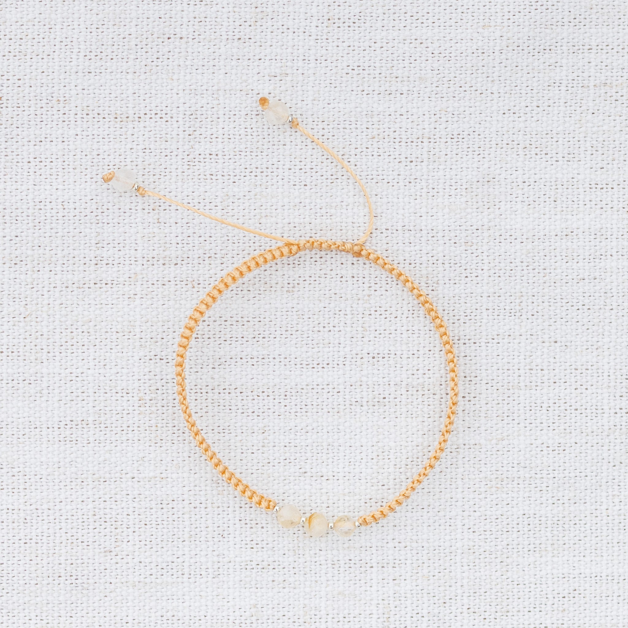 Intuitive Charms Eos's Guard Citrine Braided natural Crystal beaded custom Bracelet in silver and yellow cord on a light fabric background