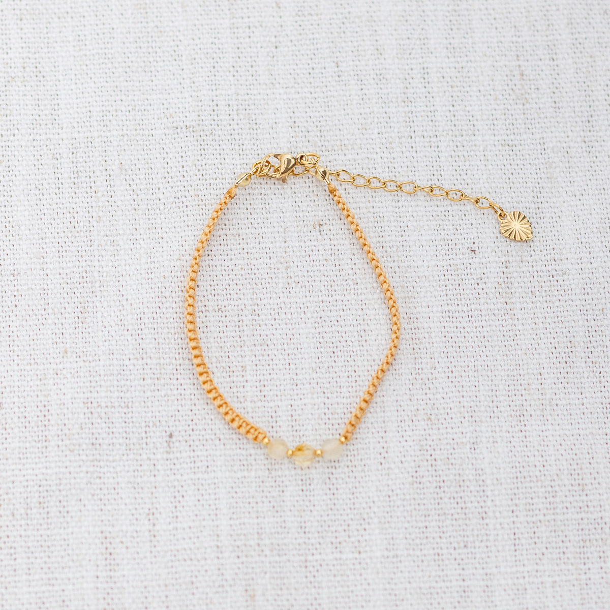 Intuitive Charms Eos's Guard Citrine Braided natural Crystal beaded custom Bracelet in gold and yellow cord and clasp extension on a light fabric background