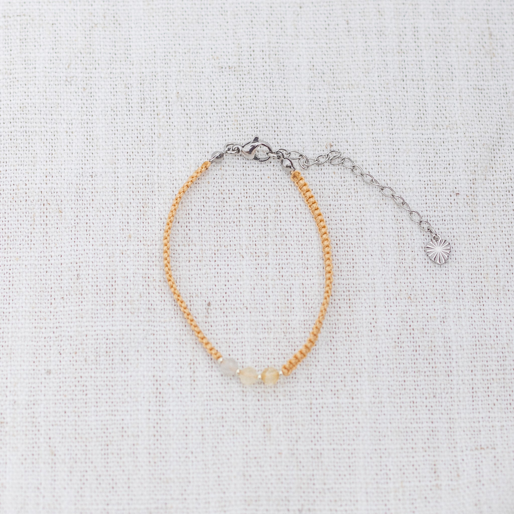 Intuitive Charms Eos's Guard Citrine Braided natural Crystal beaded custom Bracelet in silver and yellow cord and clasp extension on a light fabric background