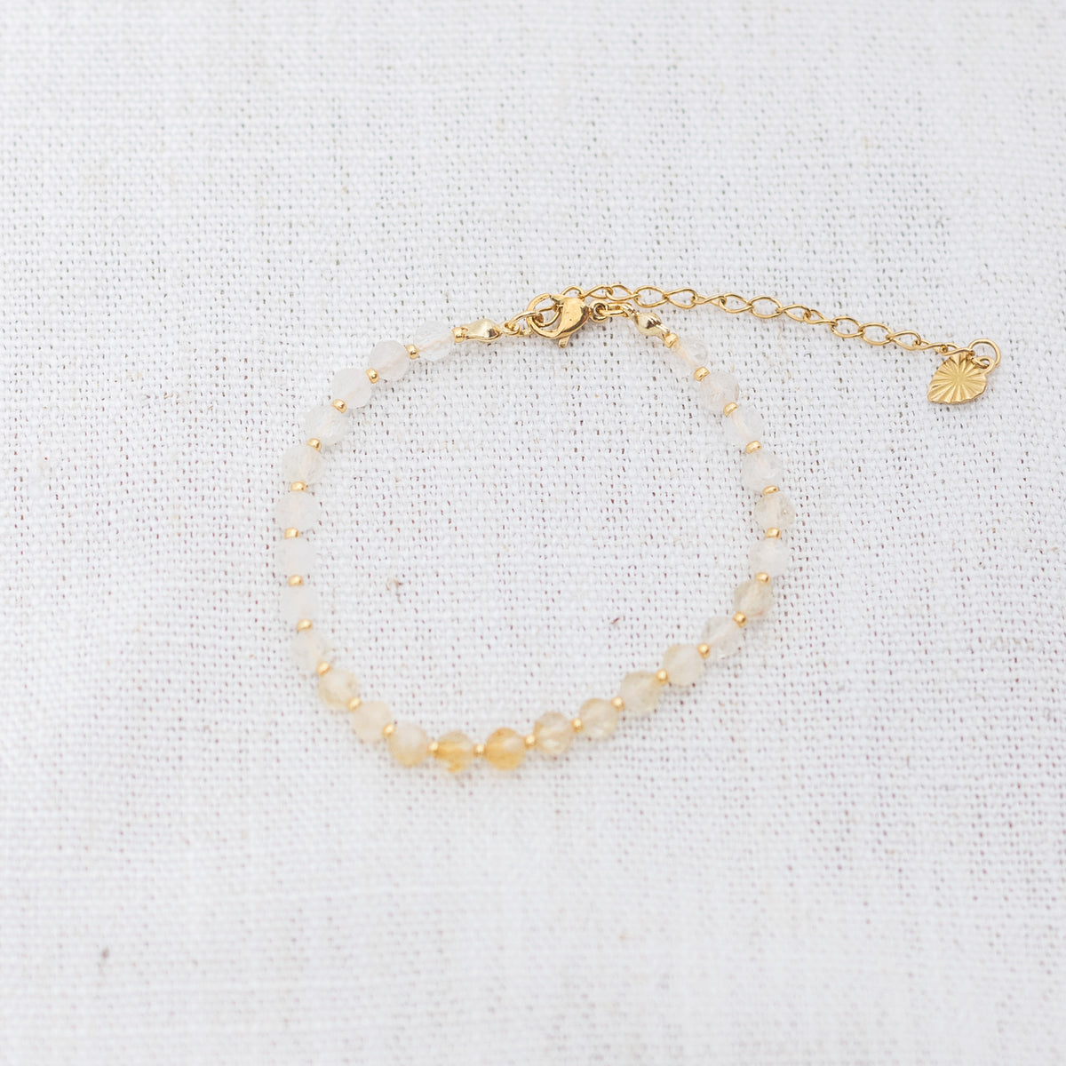 Intuitive Charms Eos's Glow Citrine Braided natural Crystal beaded custom Bracelet in gold and yellow cord and clasp extension on a light fabric background