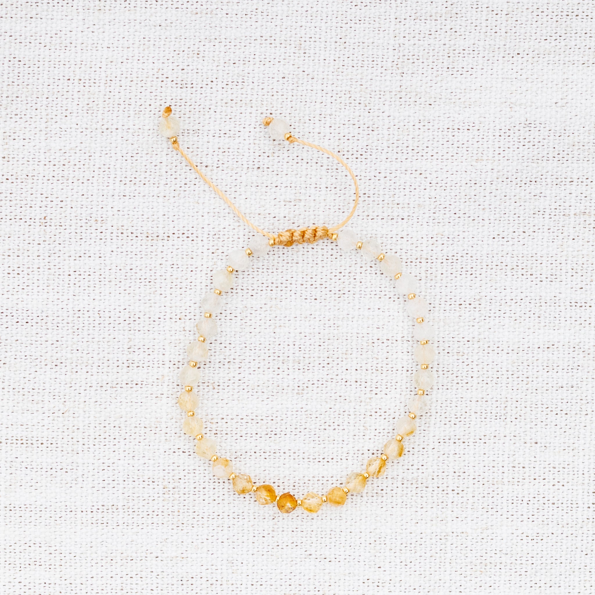 Intuitive Charms Eos's Glow Citrine Braided natural Crystal beaded custom Bracelet in gold and yellow cord on a light fabric background