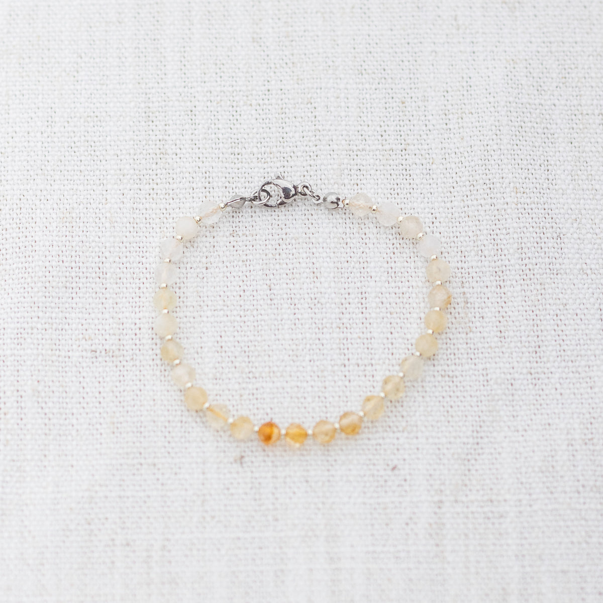Intuitive Charms Eos's Glow Citrine Braided natural Crystal beaded custom Bracelet in silver and yellow cord and clasp on a light fabric background