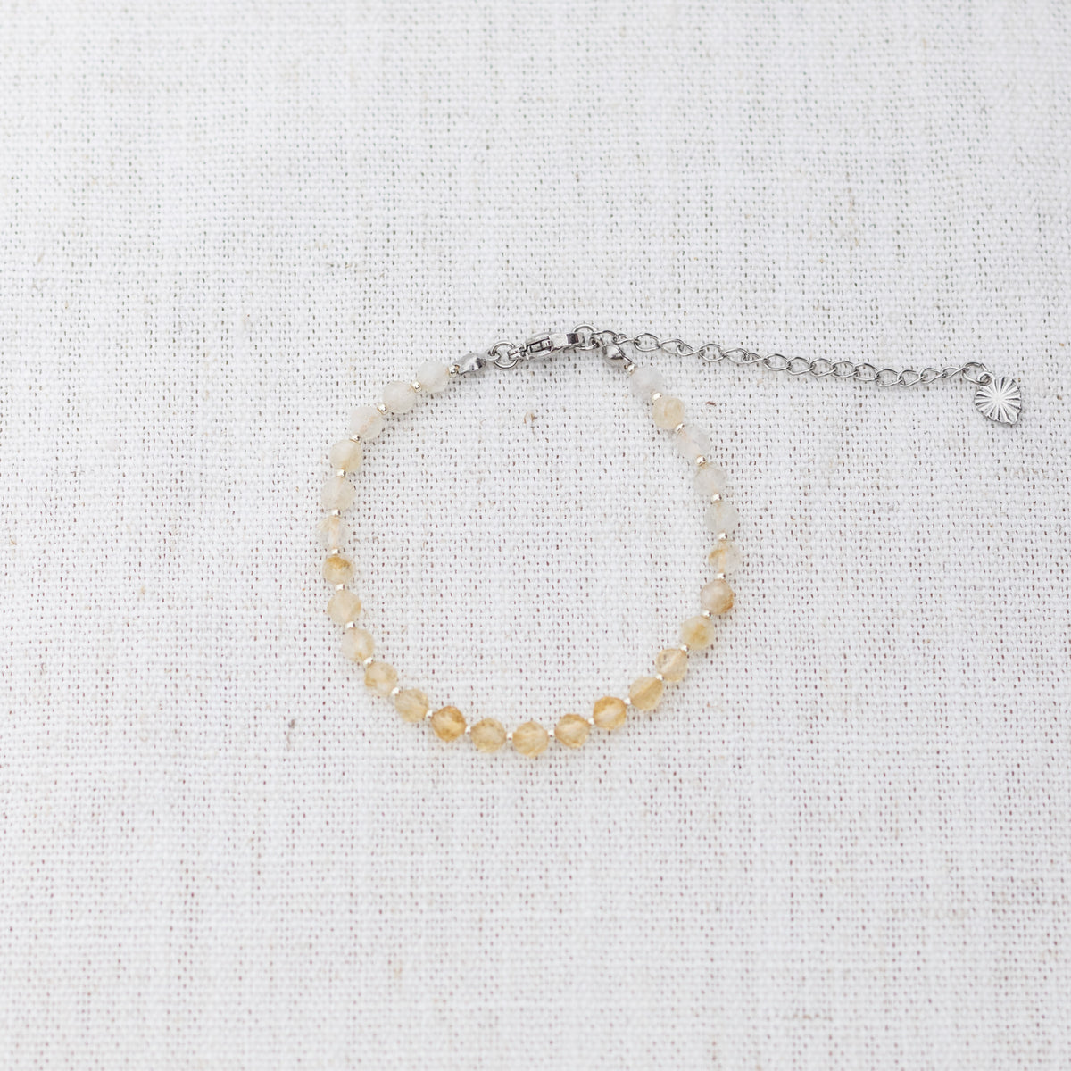Intuitive Charms Eos's Glow Citrine Braided natural Crystal beaded custom Bracelet in silver and yellow cord and clasp extension on a light fabric background