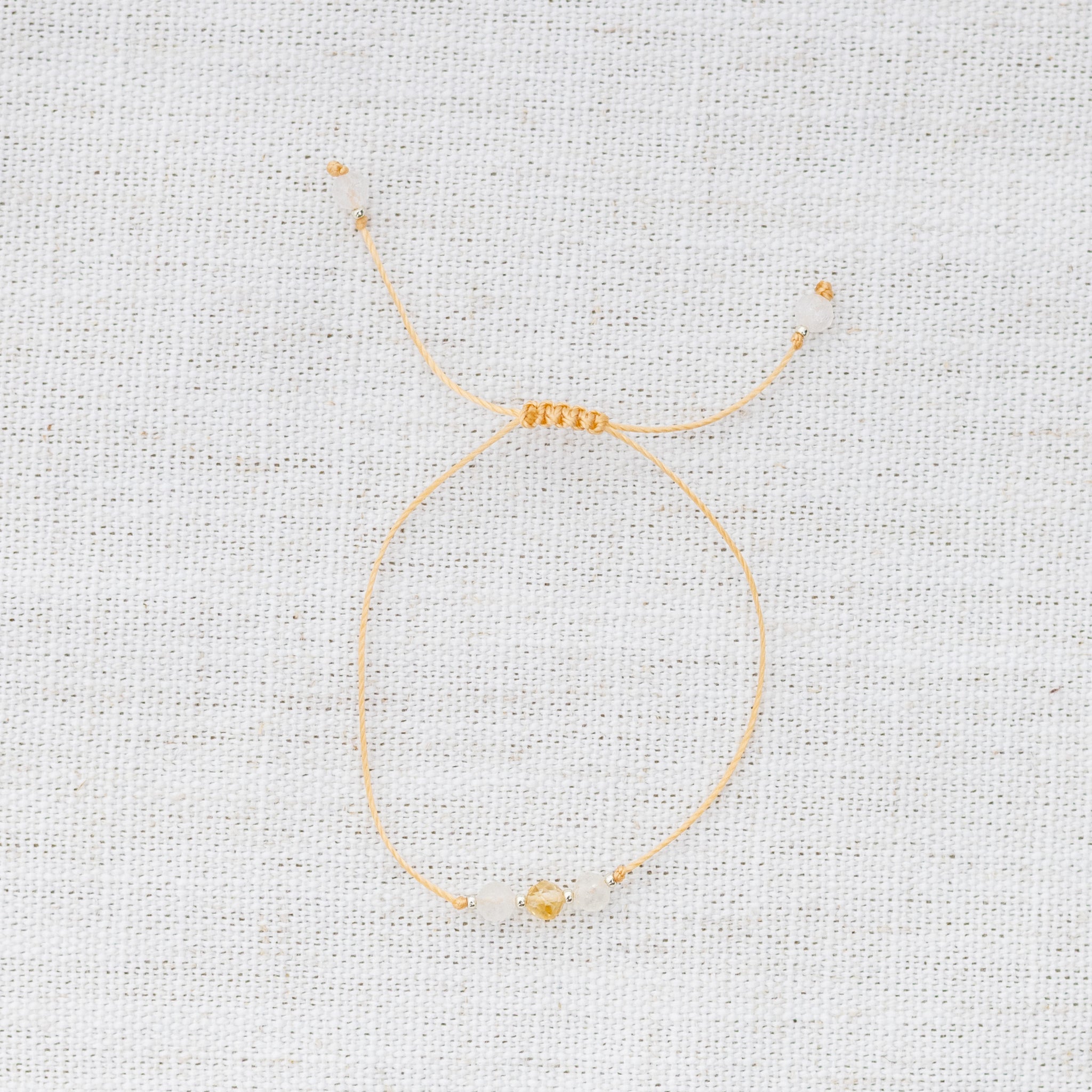 Intuitive Charms Eos's Mist Citrine Braided natural Crystal beaded custom Bracelet in silver and yellow cord on a light fabric background