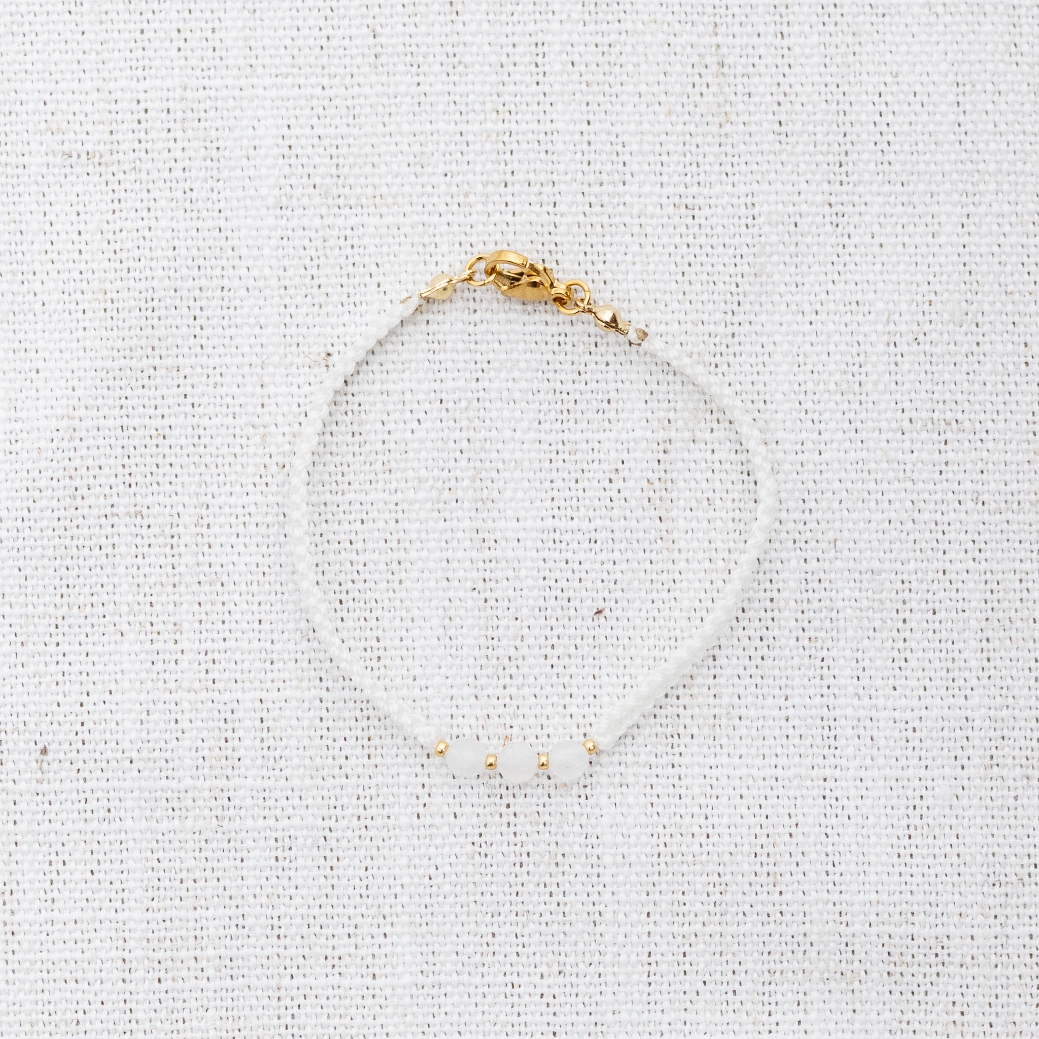 Intuitive Charms Selene's Guard Moonstone Braided natural Crystal beaded custom Bracelet in gold and white cord and clasp on a light fabric background