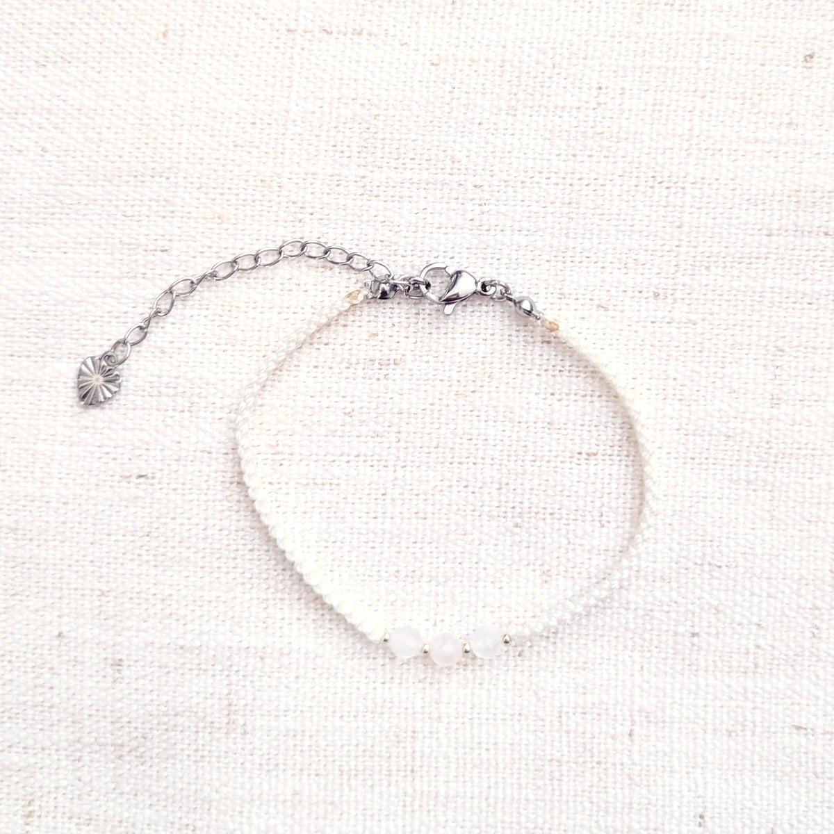 Intuitive Charms Selene's Guard Moonstone Braided natural Crystal beaded custom Bracelet in silver and white cord and clasp extension on a light fabric background