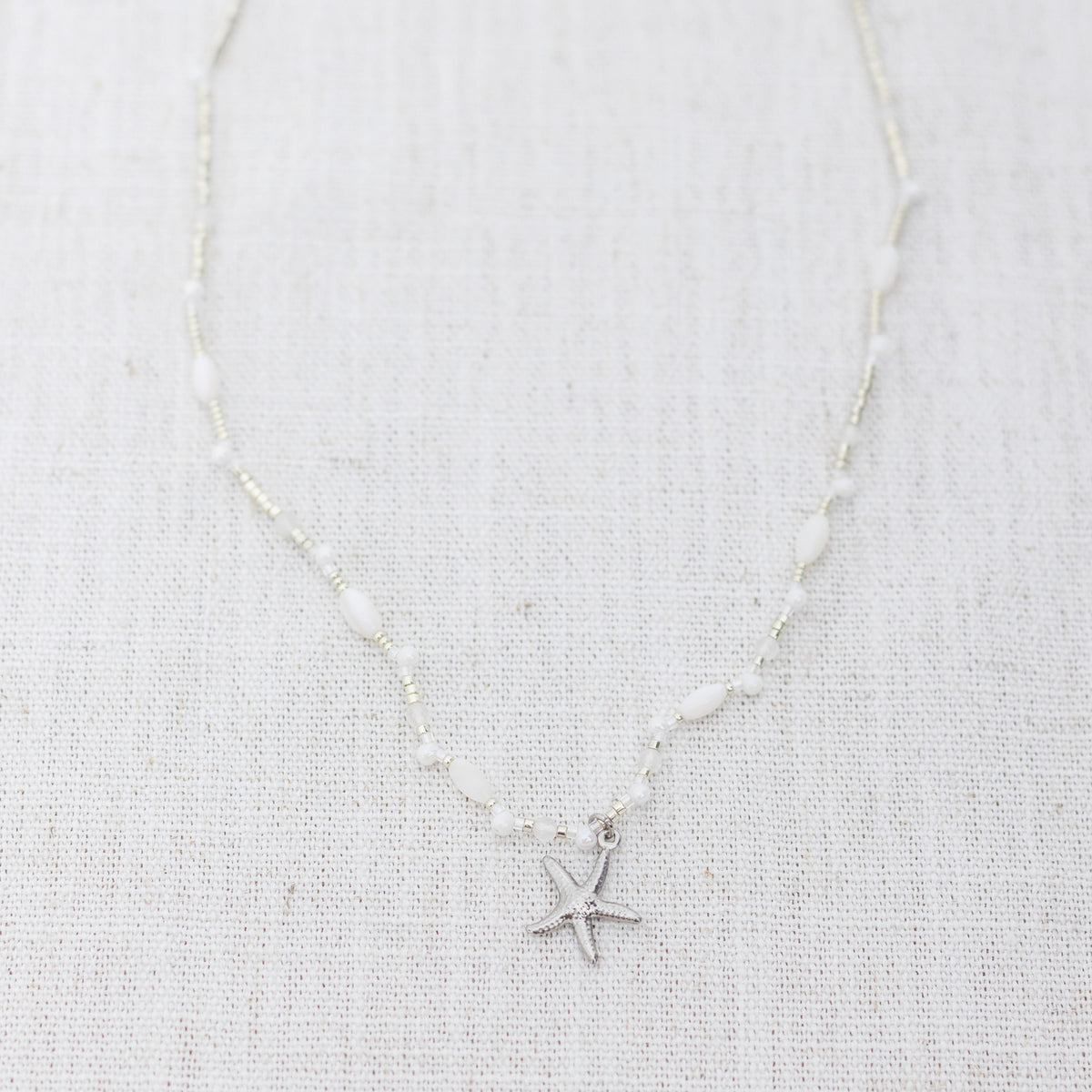 Intuitive Charms Selene's Song Moonstone natural Crystal beaded custom necklace in silver and clasp extension on a light fabric background
