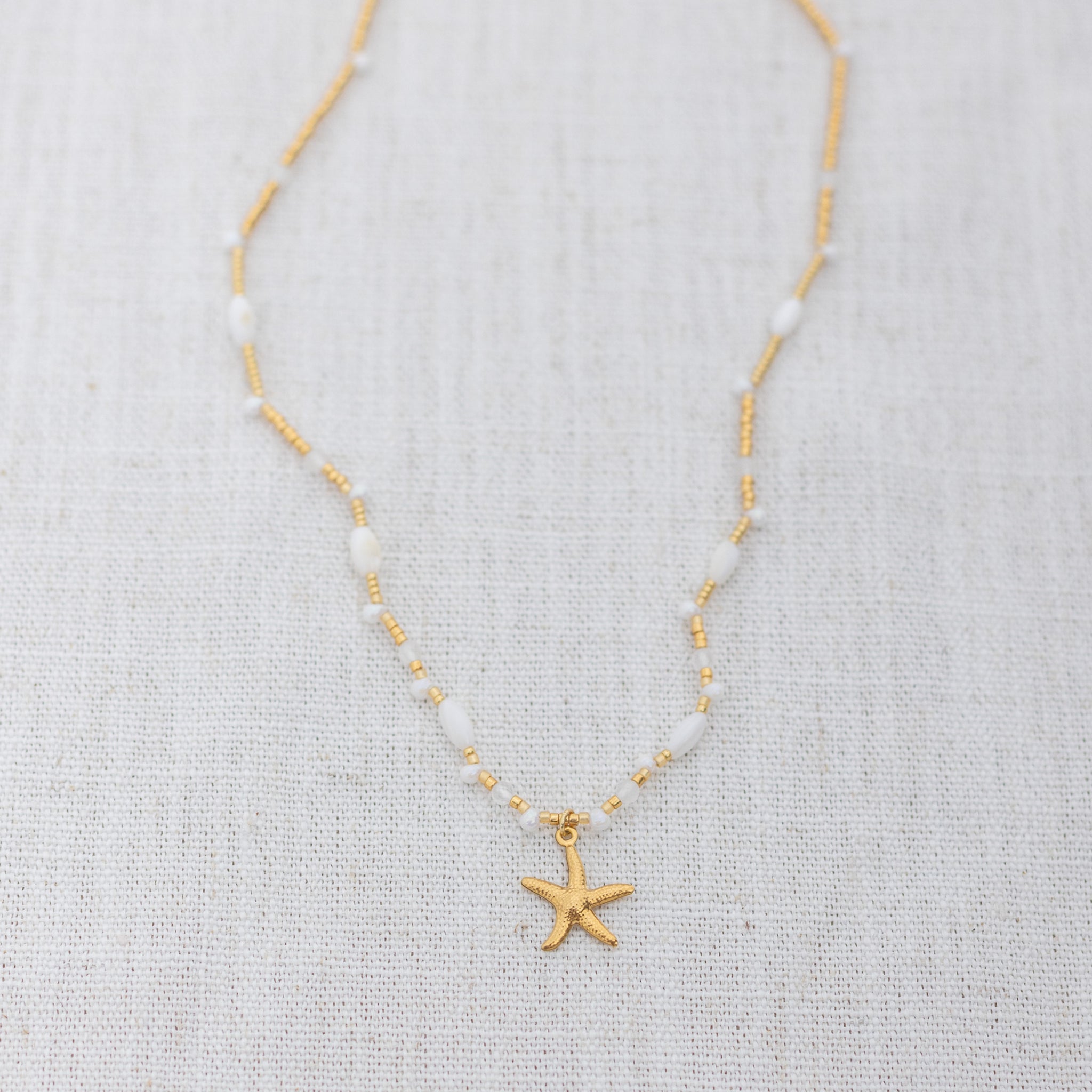 Intuitive Charms Selene's Song Moonstone natural Crystal beaded custom necklace in gold and clasp extension on a light fabric background