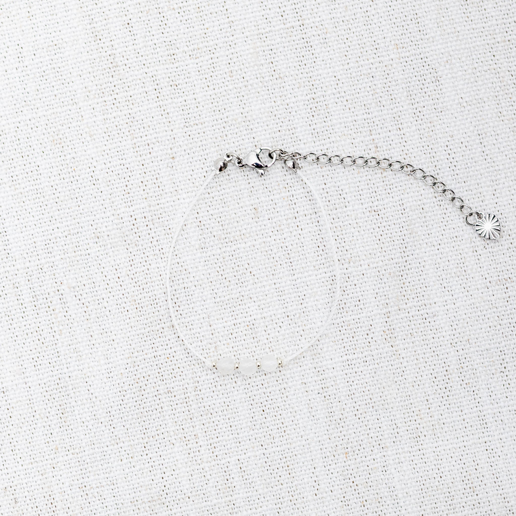 Intuitive Charms Selene's Mist Moonstone Braided natural Crystal beaded custom Bracelet in silver and white cord and clasp extension on a light fabric background