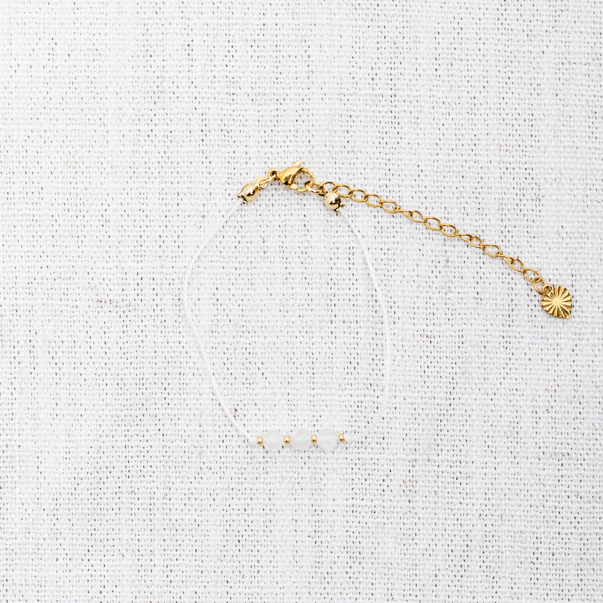 Intuitive Charms Selene's Mist Moonstone Braided natural Crystal beaded custom Bracelet in gold and white cord and clasp extension on a light fabric background