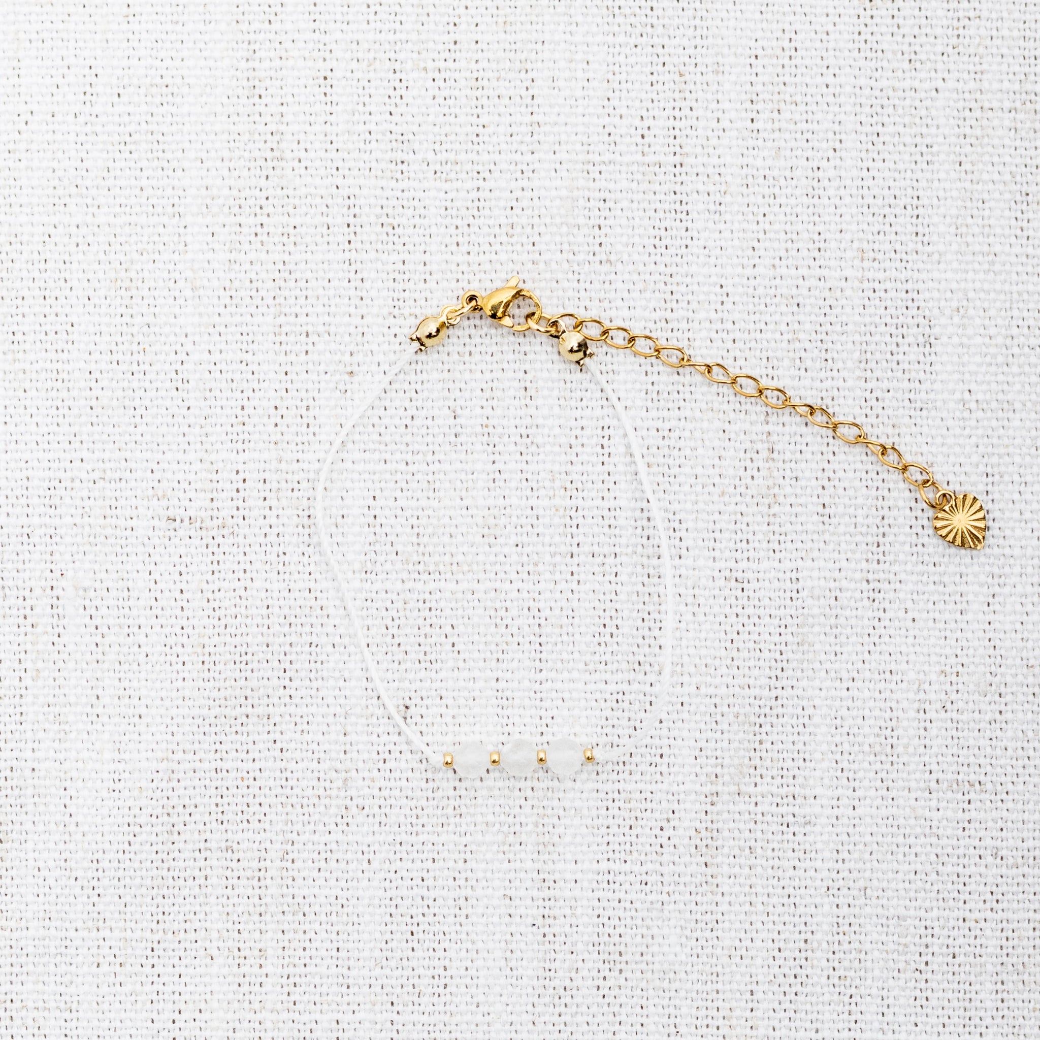 Intuitive Charms Selene's Mist Moonstone Braided natural Crystal beaded custom Bracelet in gold and white cord and clasp extension on a light fabric background