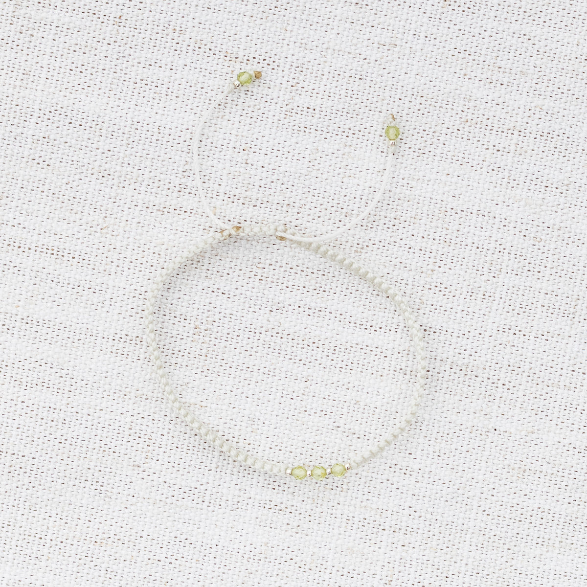 Intuitive Charms Nerina's Guard Peridot Braided natural Crystal beaded custom Bracelet in silver and light mint cord on a light fabric background