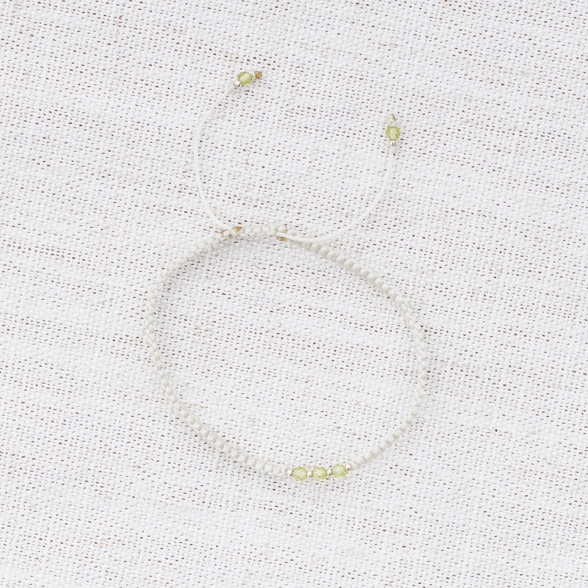 Intuitive Charms Nerina's Guard Peridot Braided natural Crystal beaded custom Bracelet in silver and light mint cord on a light fabric background