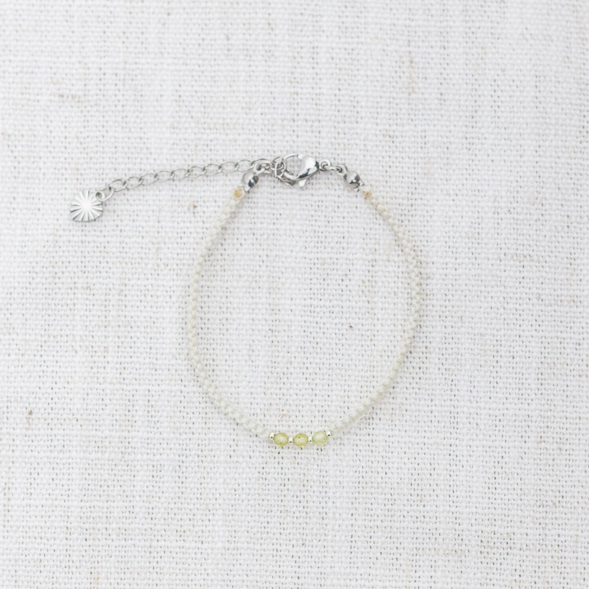 Intuitive Charms Nerina's Guard Peridot Braided natural Crystal beaded custom Bracelet in silver and light mint cord and clasp extension on a light fabric background