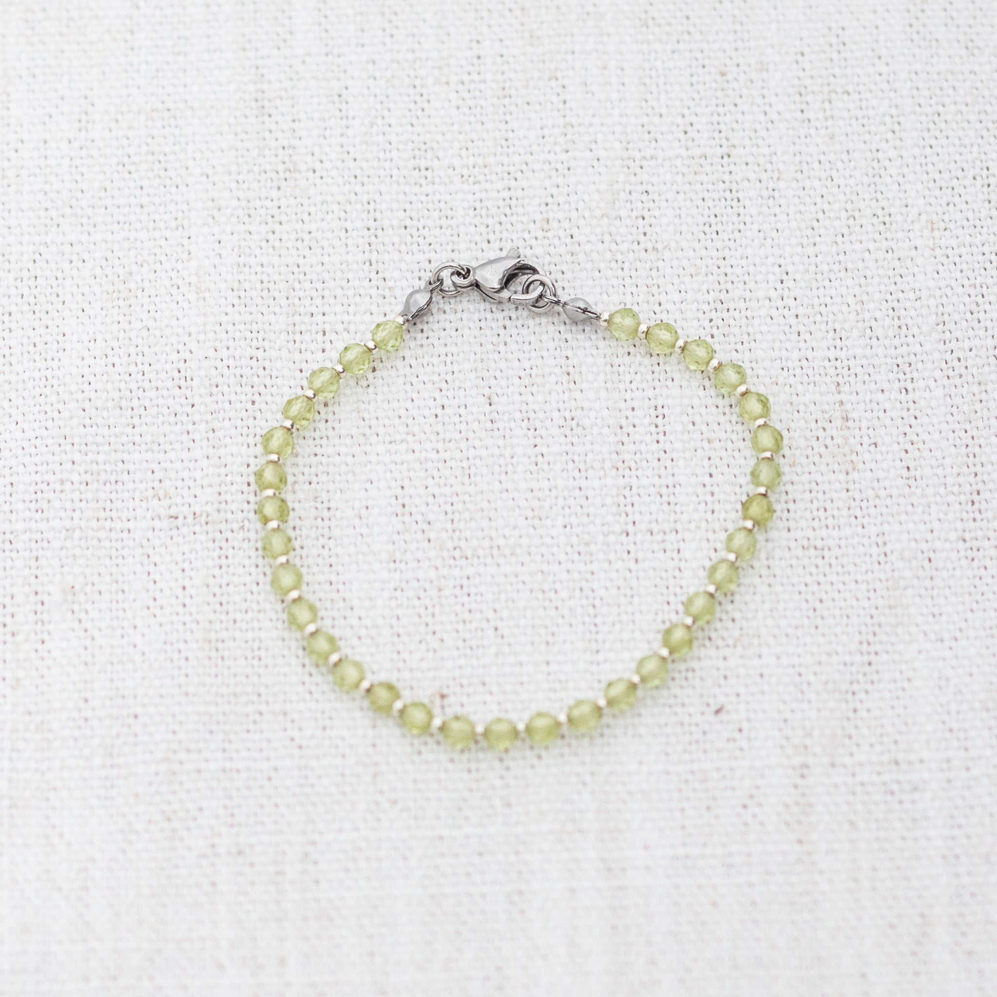 Intuitive Charms Nerina's Glow Peridot Braided natural Crystal beaded custom Bracelet in silver and light mint cord and clasp on a light fabric background