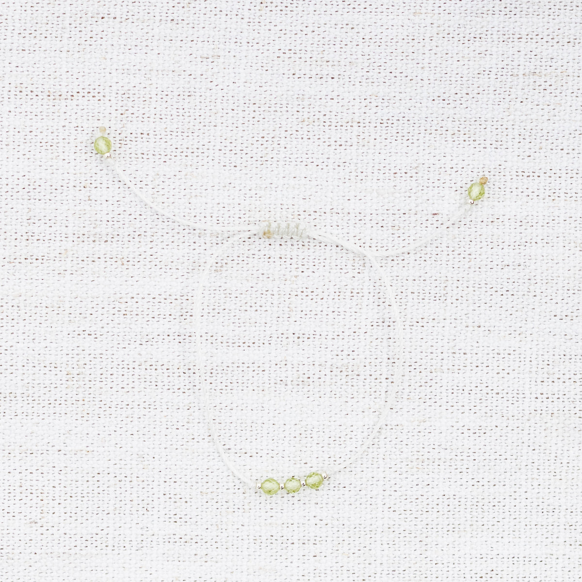 Intuitive Charms Nerina's Mist Peridot Braided natural Crystal beaded custom Bracelet in silver and light mint cord on a light fabric background