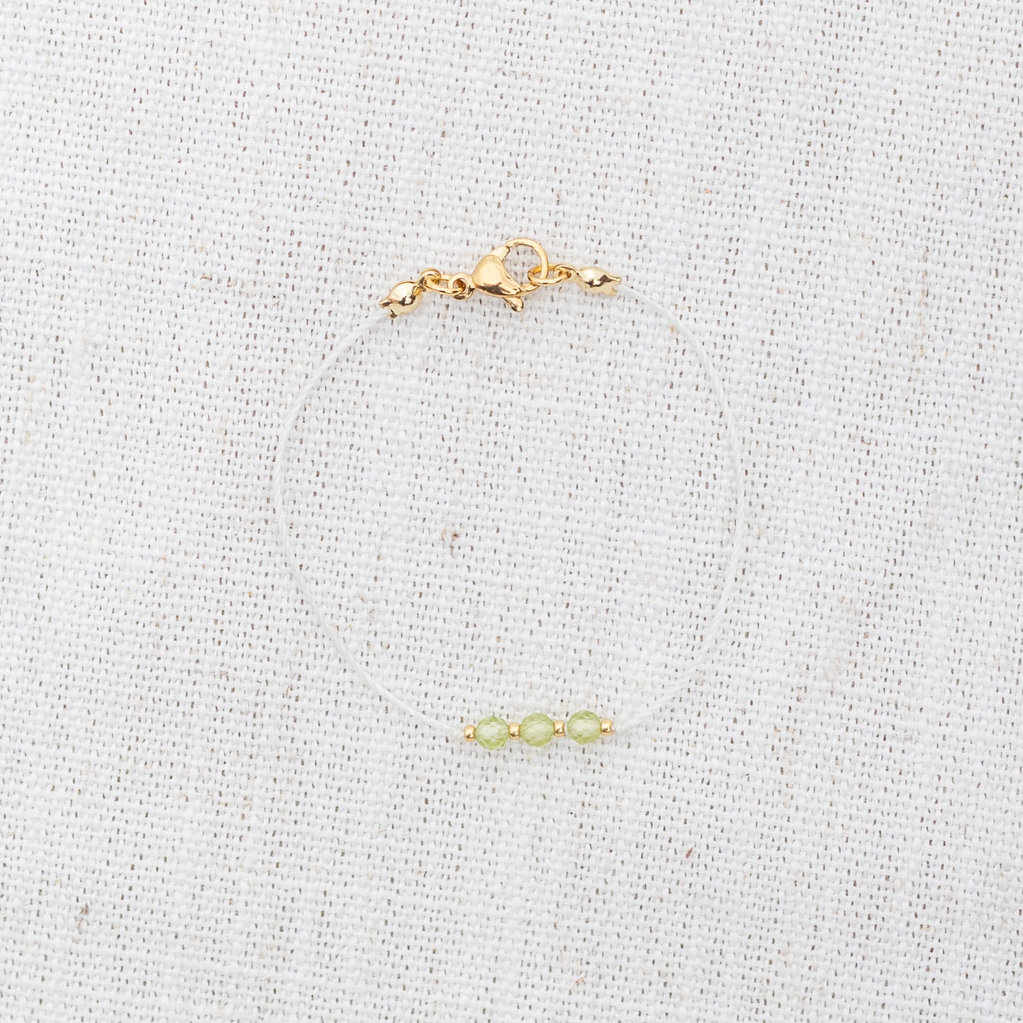 Intuitive Charms Nerina's Mist Peridot Braided natural Crystal beaded custom Bracelet in gold and light mint cord and clasp on a light fabric background