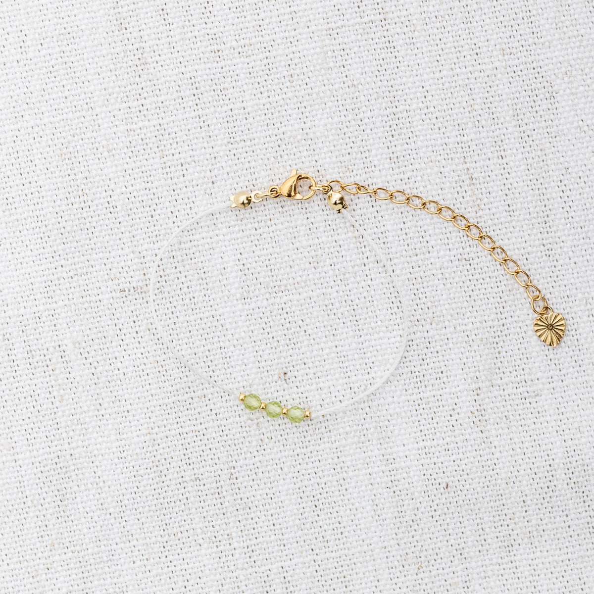 Intuitive Charms Nerina's Mist Peridot Braided natural Crystal beaded custom Bracelet in gold and light mint cord and clasp extension on a light fabric background