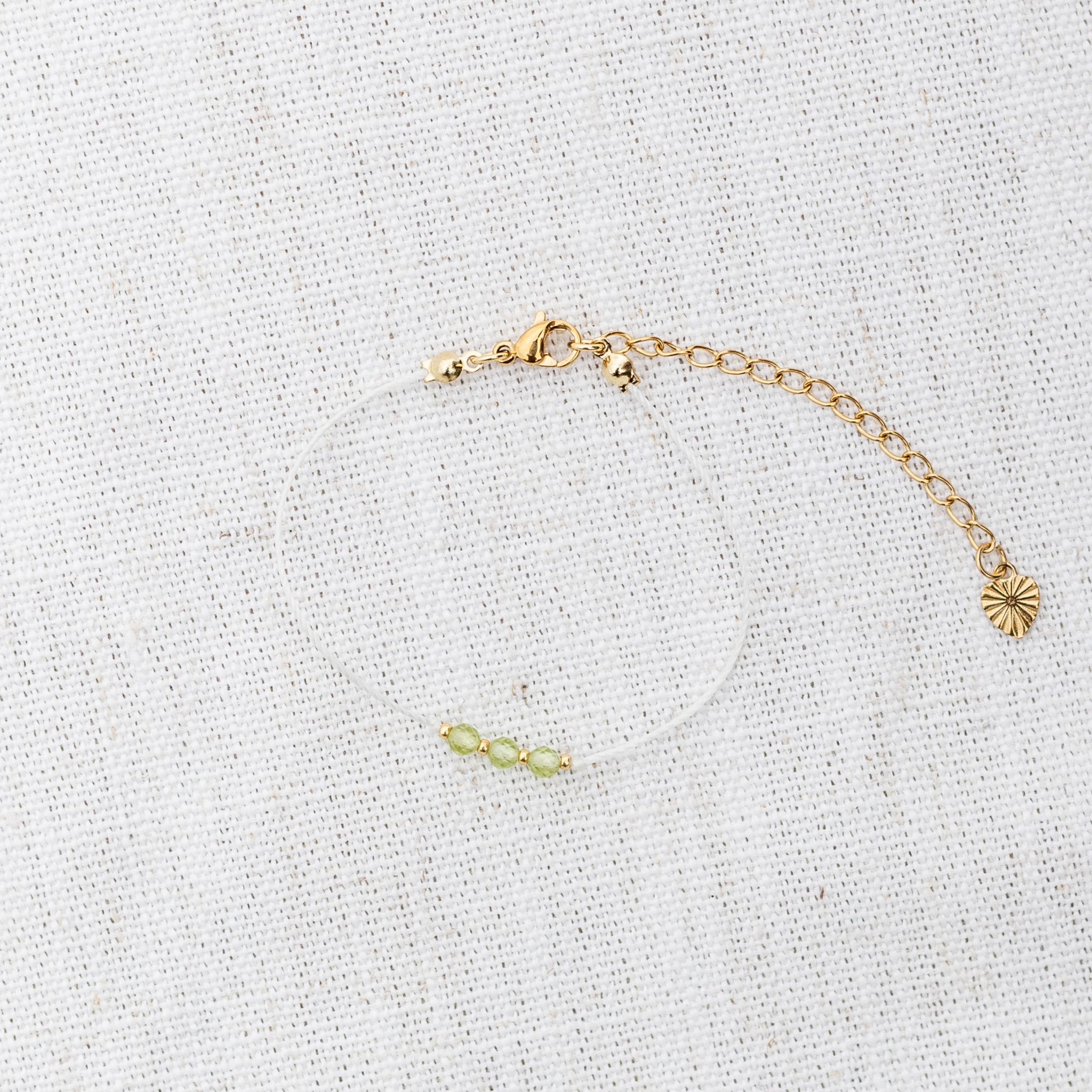 Intuitive Charms Nerina's Mist Peridot Braided natural Crystal beaded custom Bracelet in gold and light mint cord and clasp extension on a light fabric background
