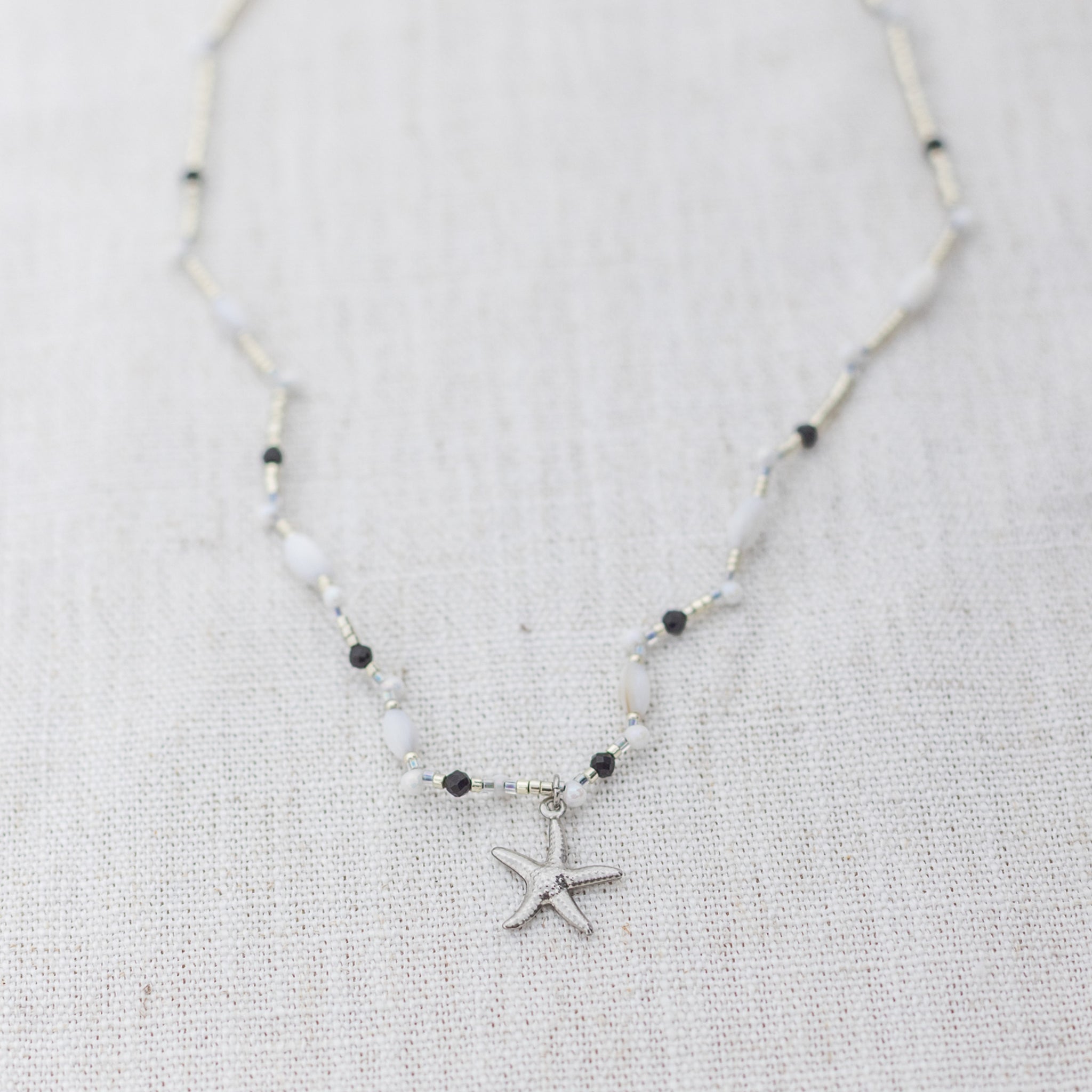 Intuitive Charms Ceto's Song Black tourmaline Braided natural Crystal beaded custom necklace in silver and black cord on a light fabric background