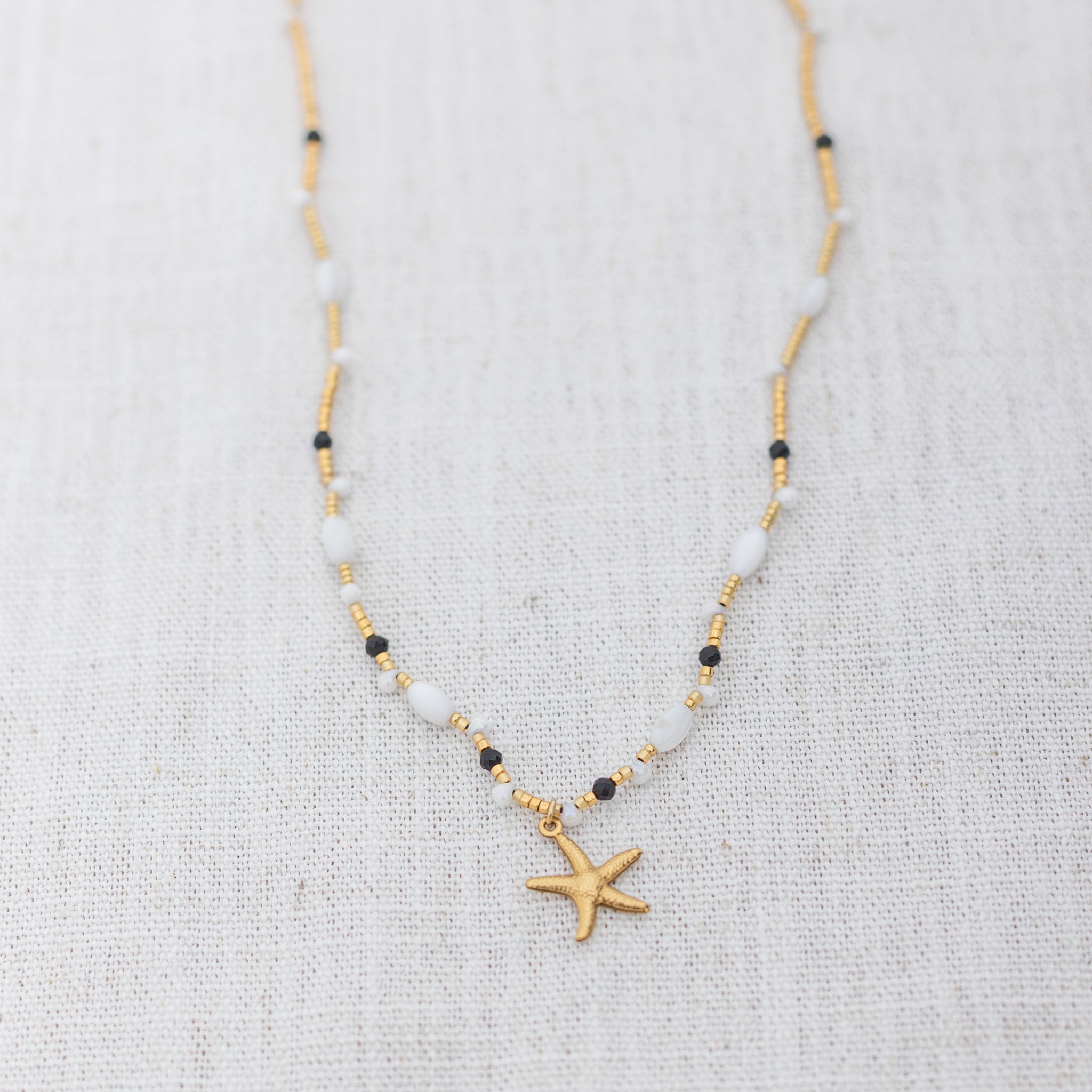 Intuitive Charms Ceto's Song Black tourmaline Braided natural Crystal beaded custom necklace in gold and black cord on a light fabric background