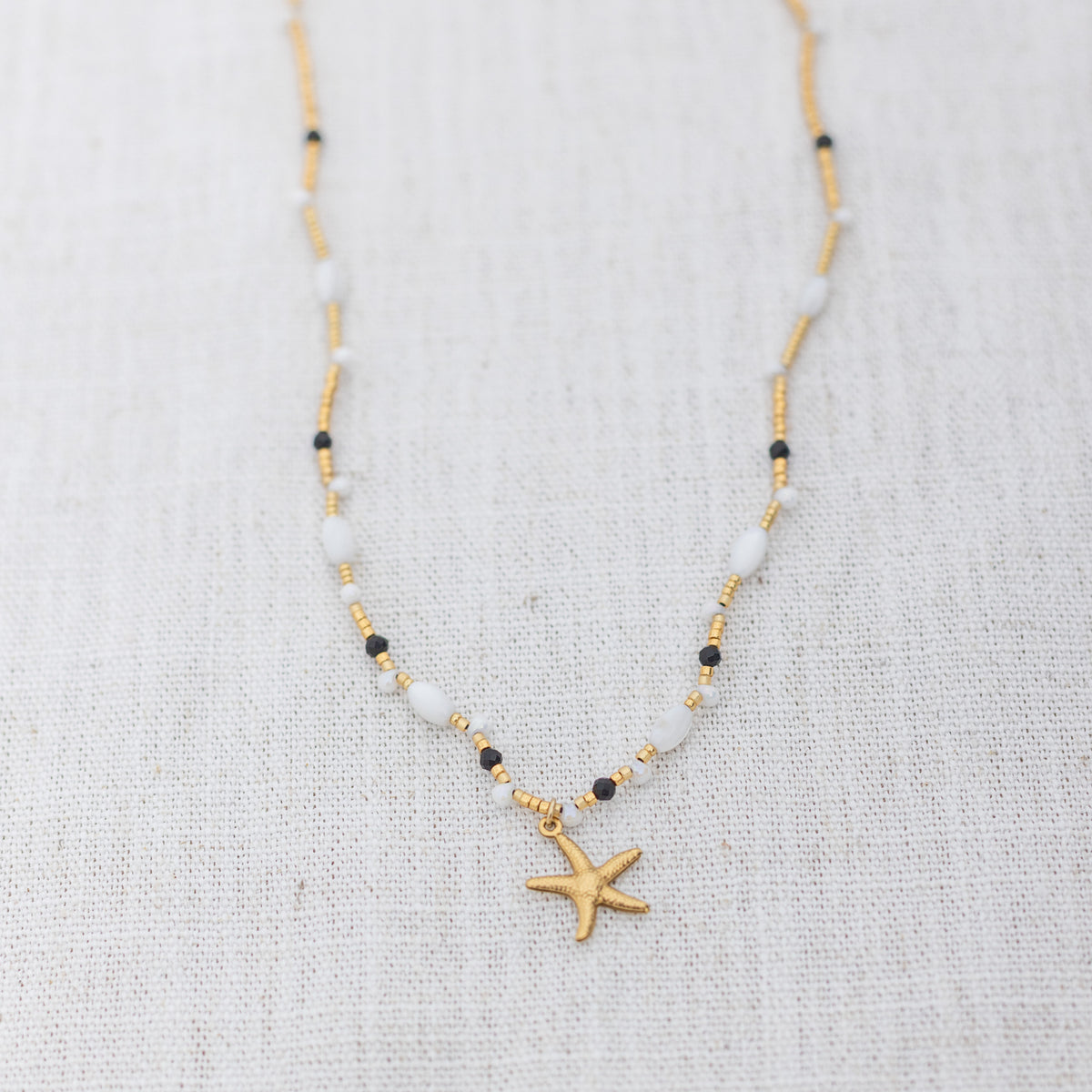 Intuitive Charms Ceto's Song Black tourmaline Braided natural Crystal beaded custom necklace in gold and black cord on a light fabric background