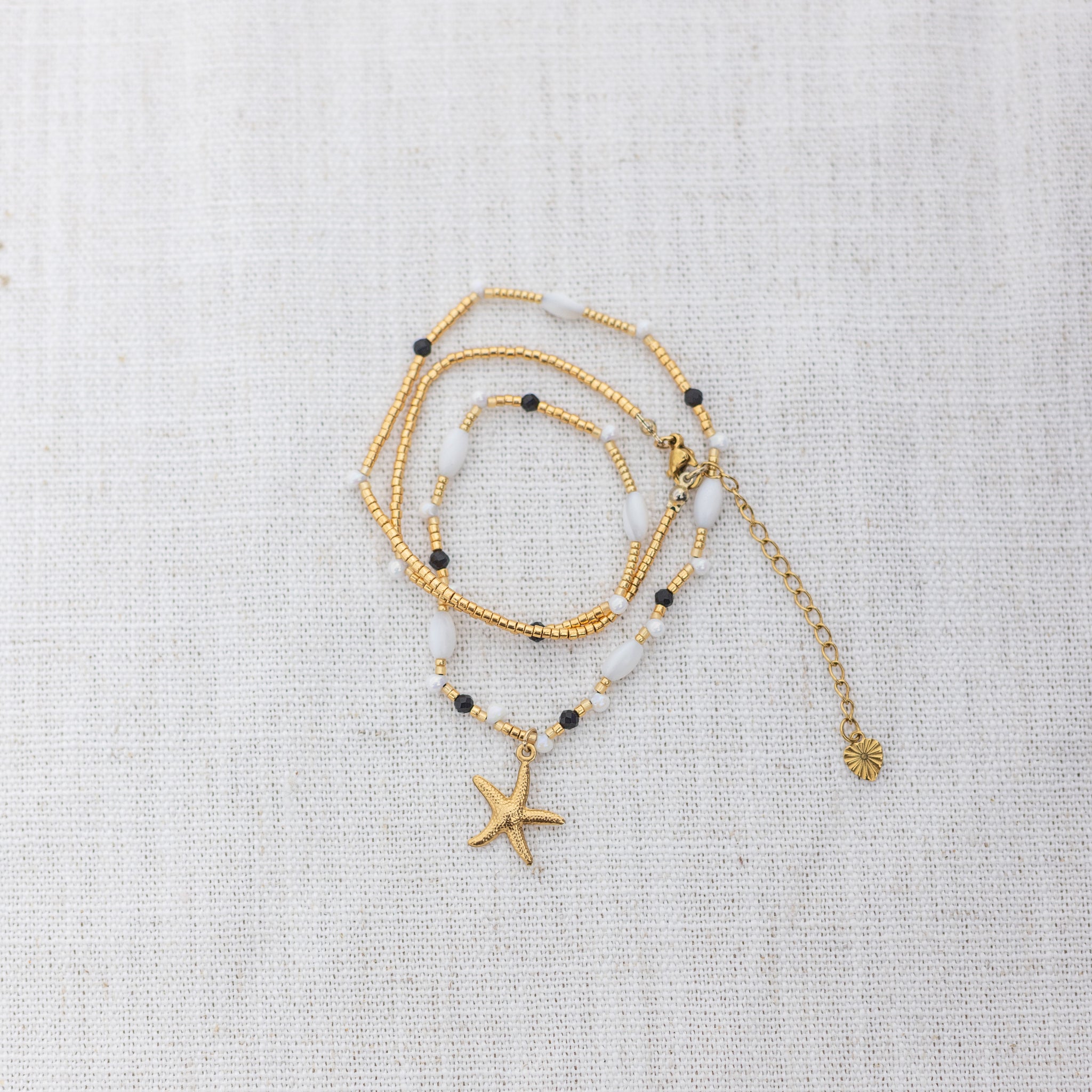 Intuitive Charms Ceto's Song Black tourmaline Braided natural Crystal beaded custom necklace in gold and black cord on a light fabric background wrapped version