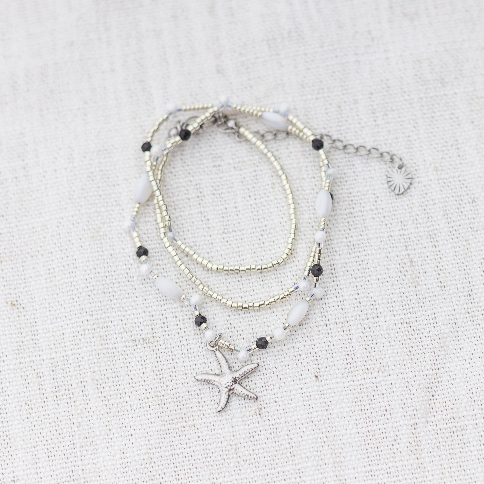 Intuitive Charms Ceto's Song Black tourmaline Braided natural Crystal beaded custom necklace in silver and black cord on a light fabric background wrapped version