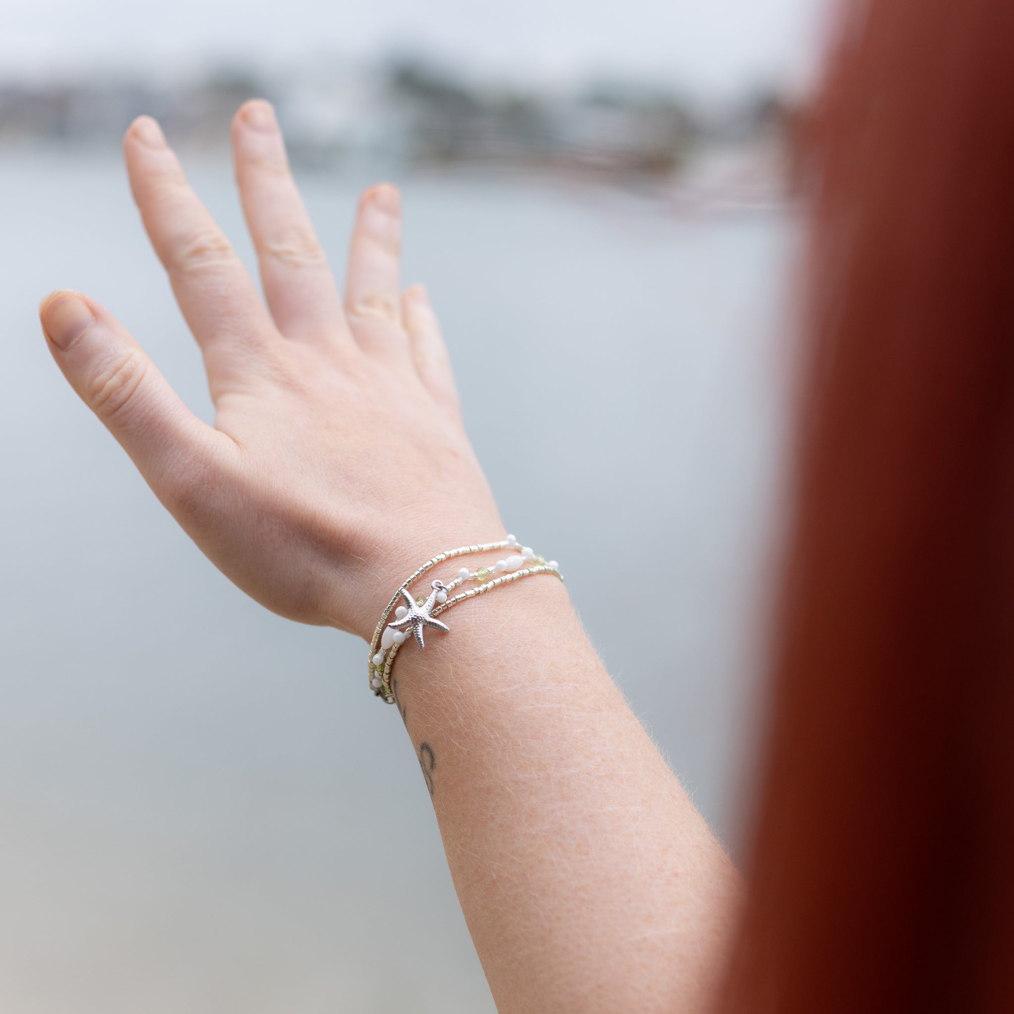 Intuitive Charms Nerina's Song Peridot natural Crystal beaded custom Bracelet in silver on a model hand reaching out to distance