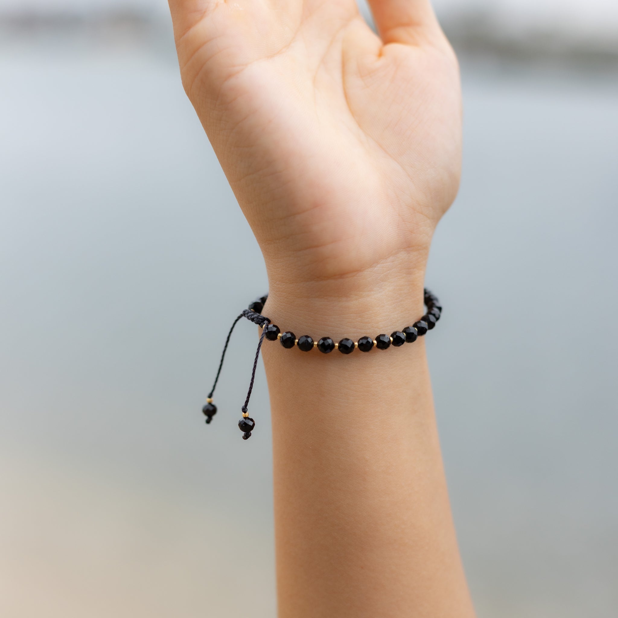 Intuitive Charms Ceto's Glow Apatite Braided natural Crystal beaded custom Bracelet in gold and black cord on a hand model
