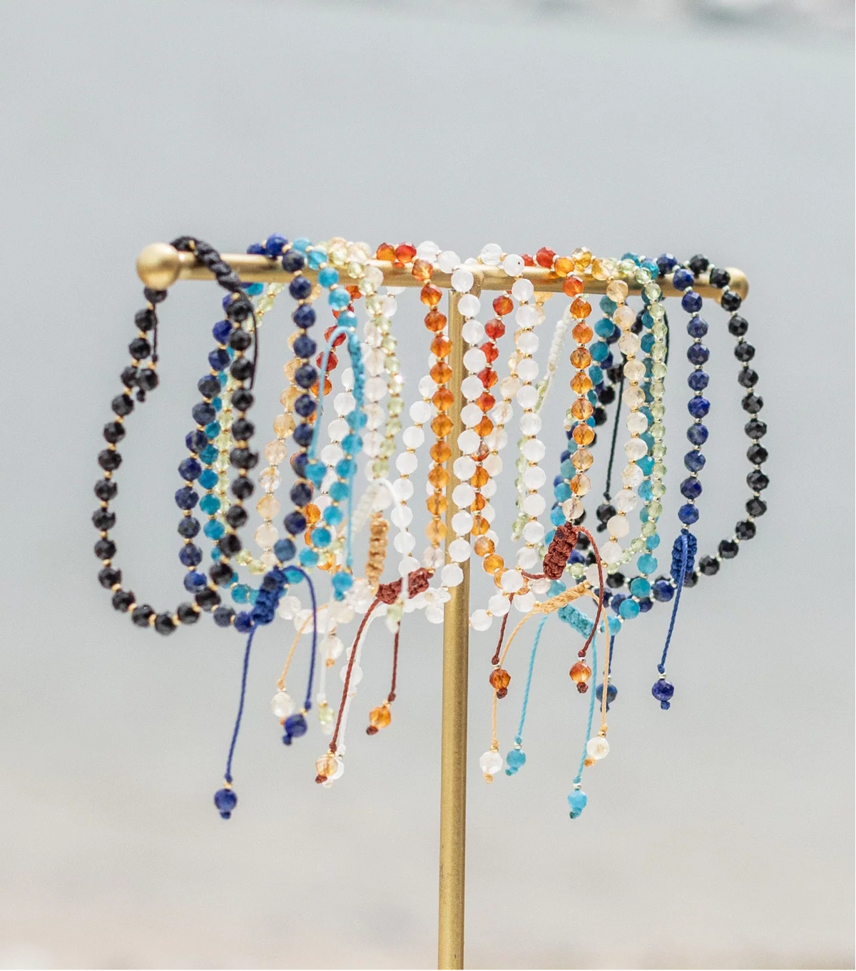 Apatite Black tourmaline lapis lazuli citrine carnelian moonstone peridot bracelets on display on the beach portrait size